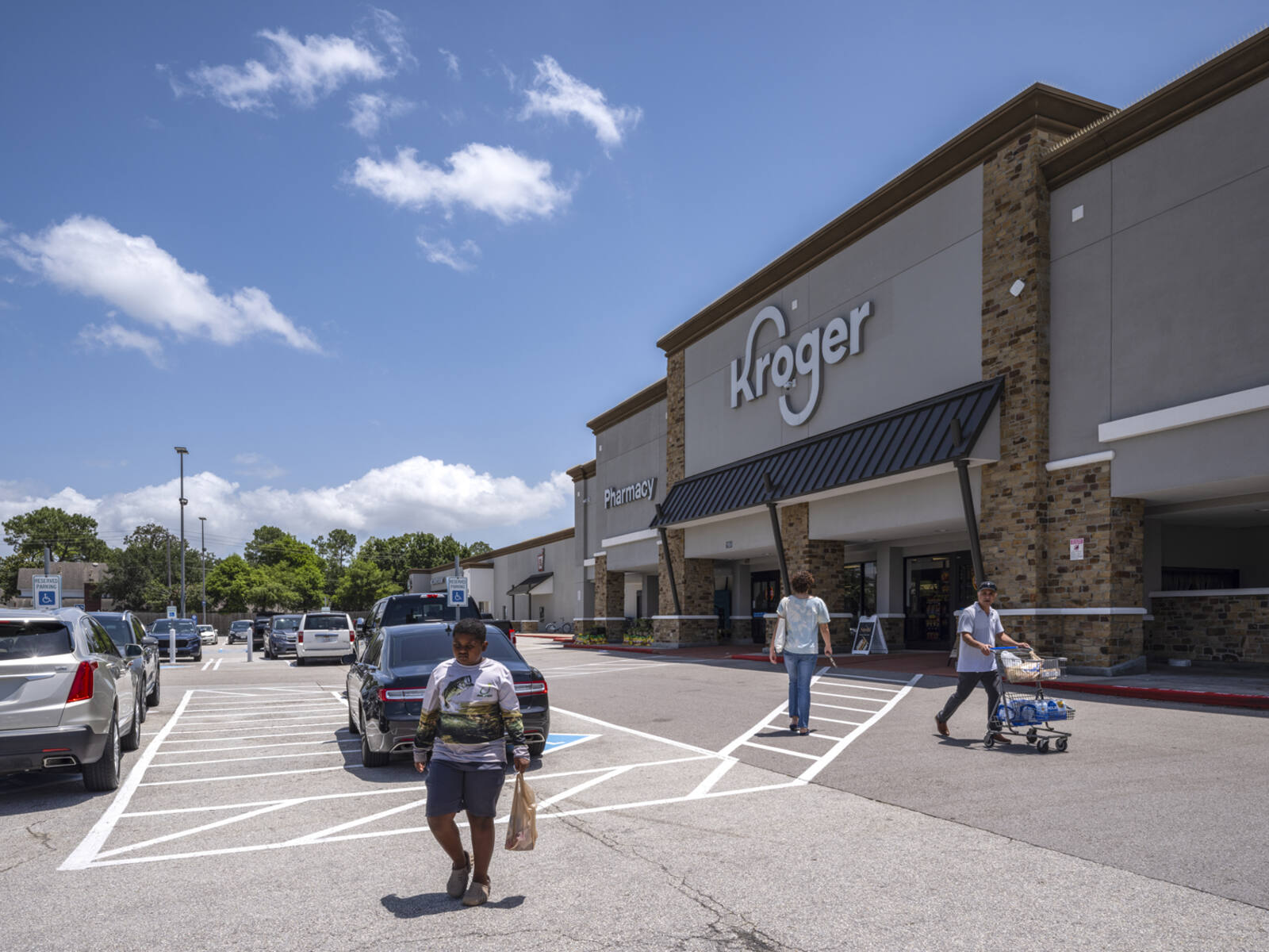 Patrons with bags and carts leaving Kroger supermarket to the parking lot.