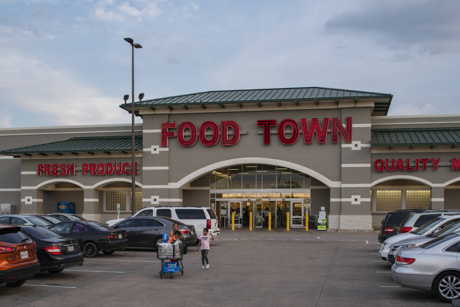 Food Town parking lot with shoppers pushing cars coming up parking aisle.