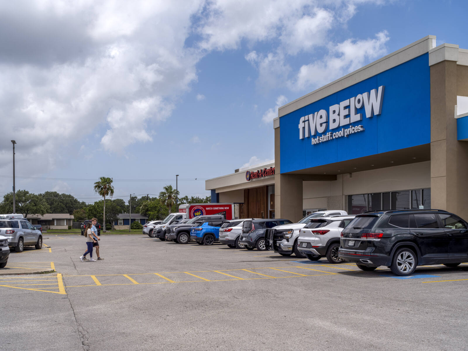 People in crosswalk for Five Below in parking lot with palm trees in background.