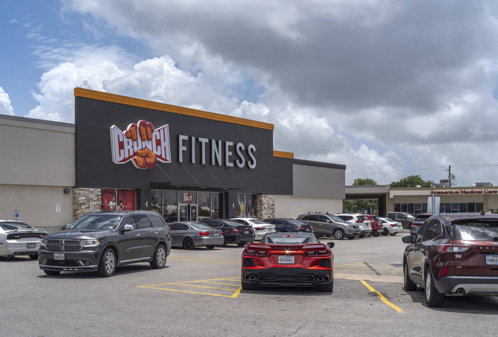 Parking lot at Crunch Fitness with grey clouds above.