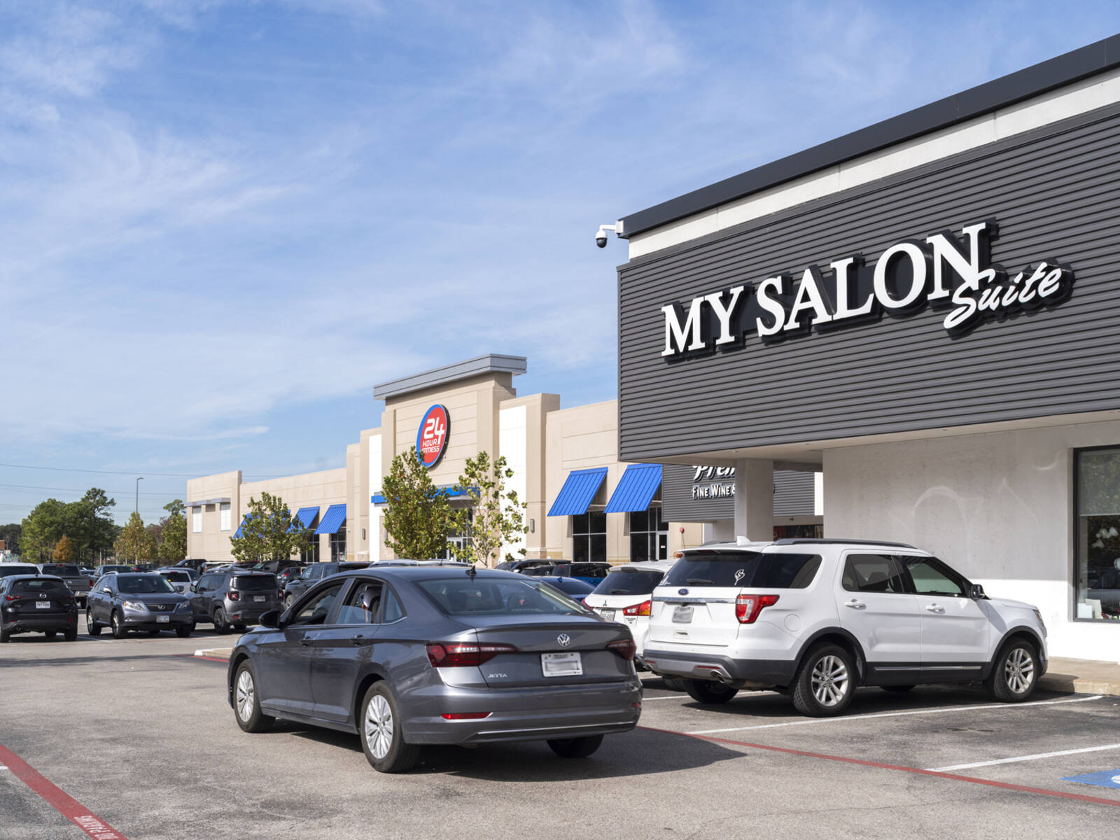 My Salon Suite and 24 Hour Fitness with busy parking lot in front.