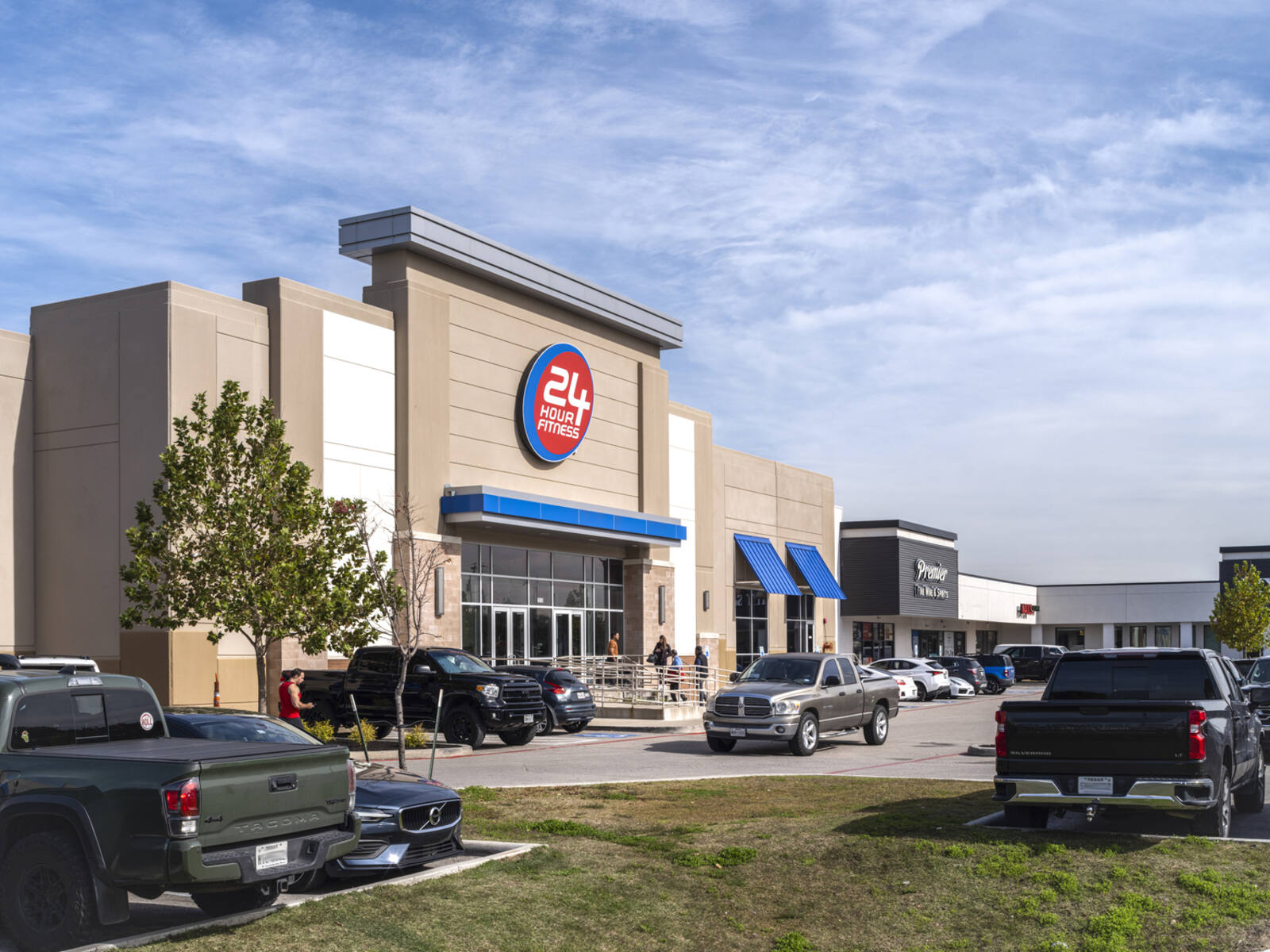 24 Hour Fitness with busy parking lot of trucks and patrons entering on a ramp.