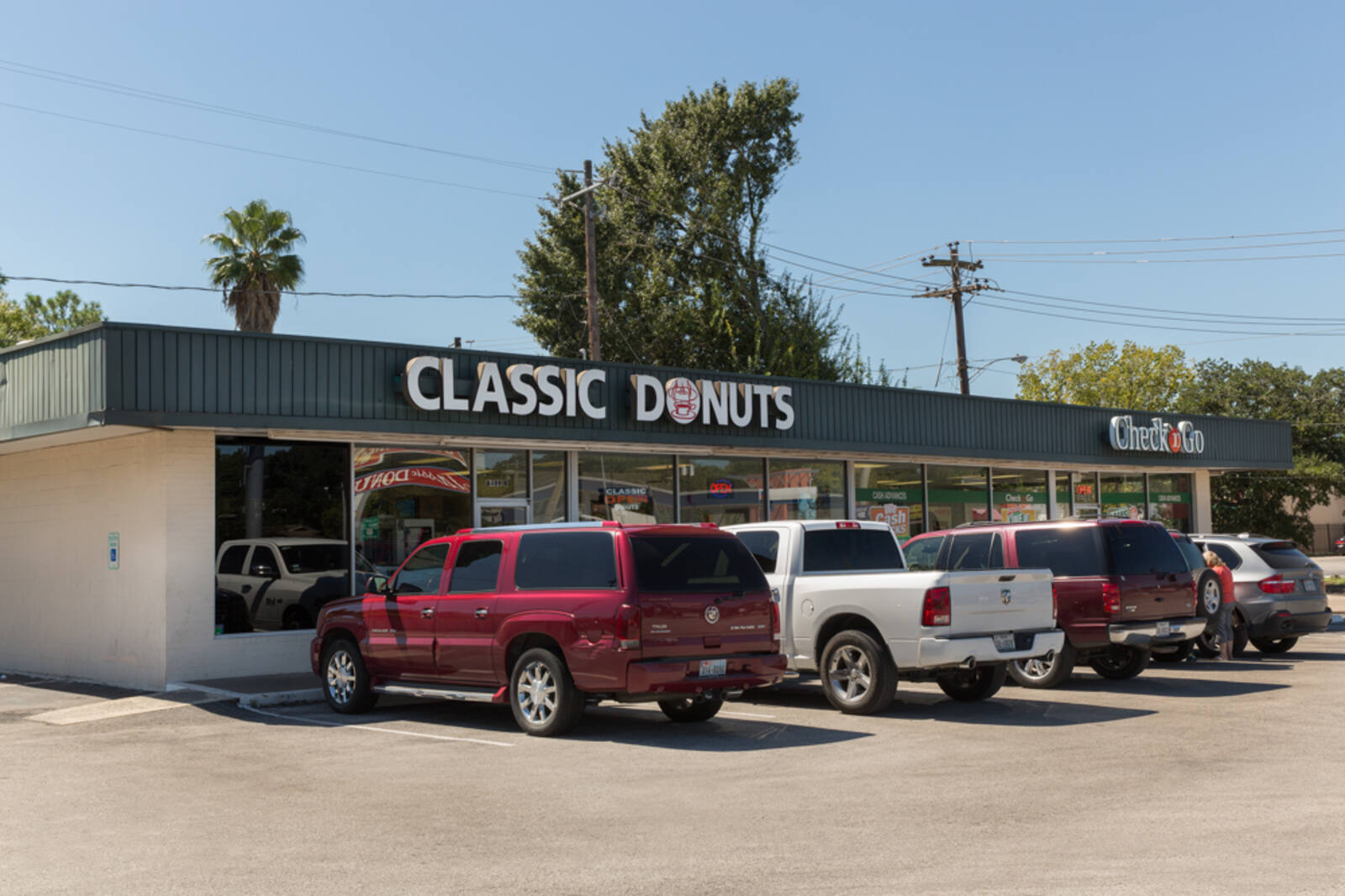 Classic Donuts with trucks, trees and palm trees in the parking lot.