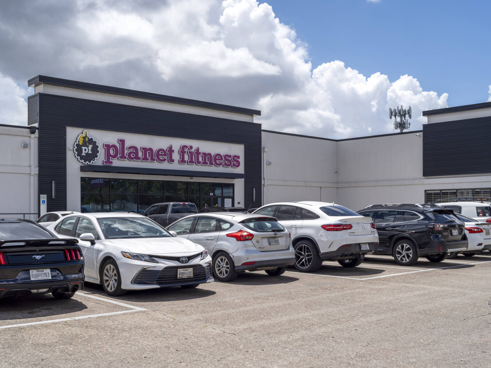Row of cars at a parking lot in front of Planet Fitness.