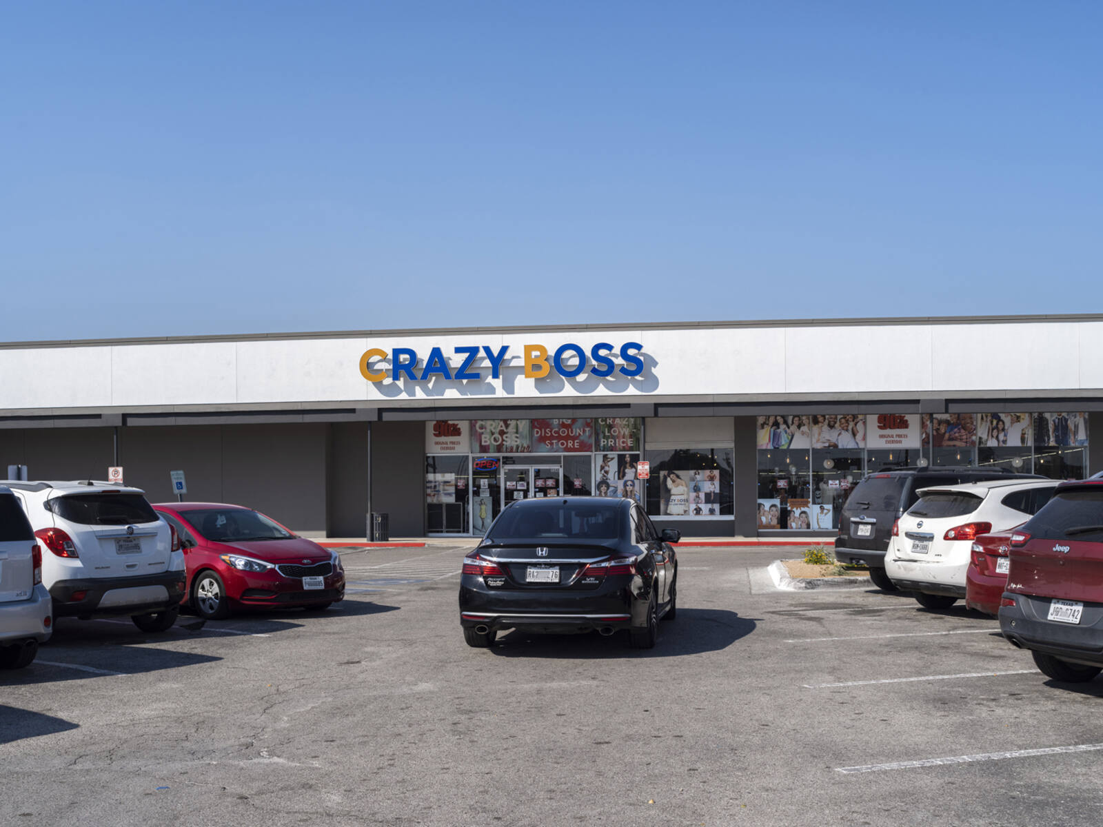 Black car drives up parking rows to Crazy Boss department store.