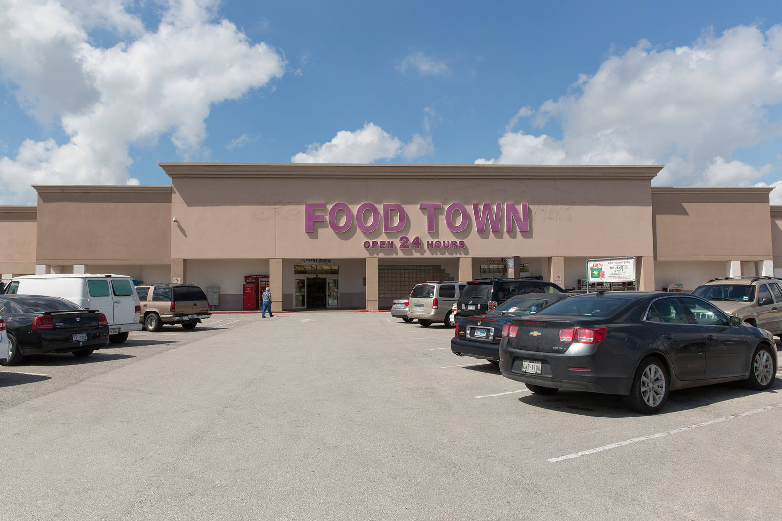 Cars parked on either side of parking lot leading to entrance of Food Town at Parktown Shopping Center
