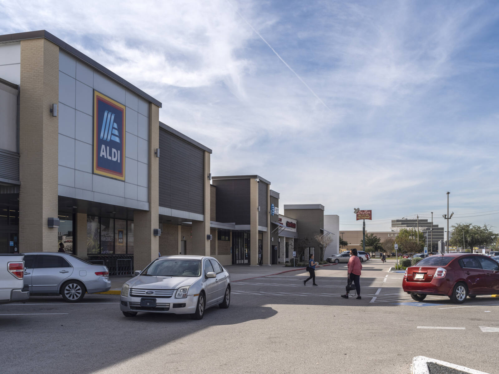 Busy crosswalk with pedestrians and cars at Aldi supermarket.