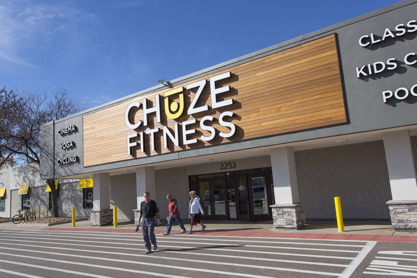 Three people walking out of Chuze Fitness Entrance