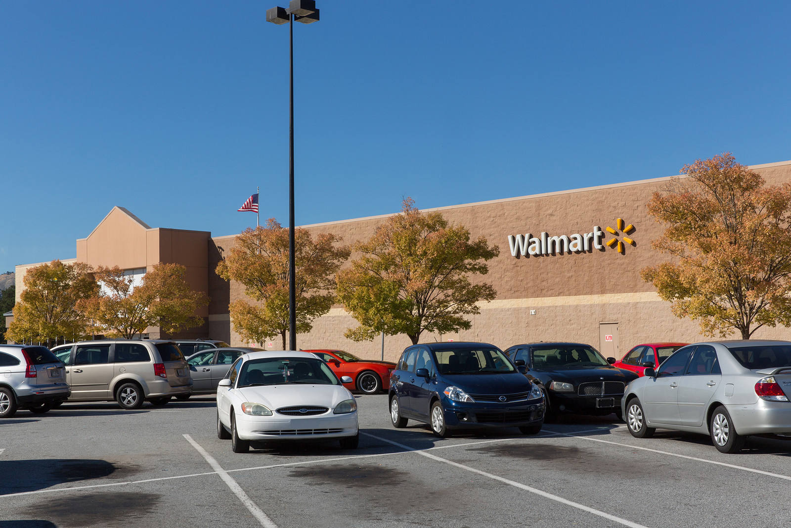 Cars parked in front of tree lined Walmart facade