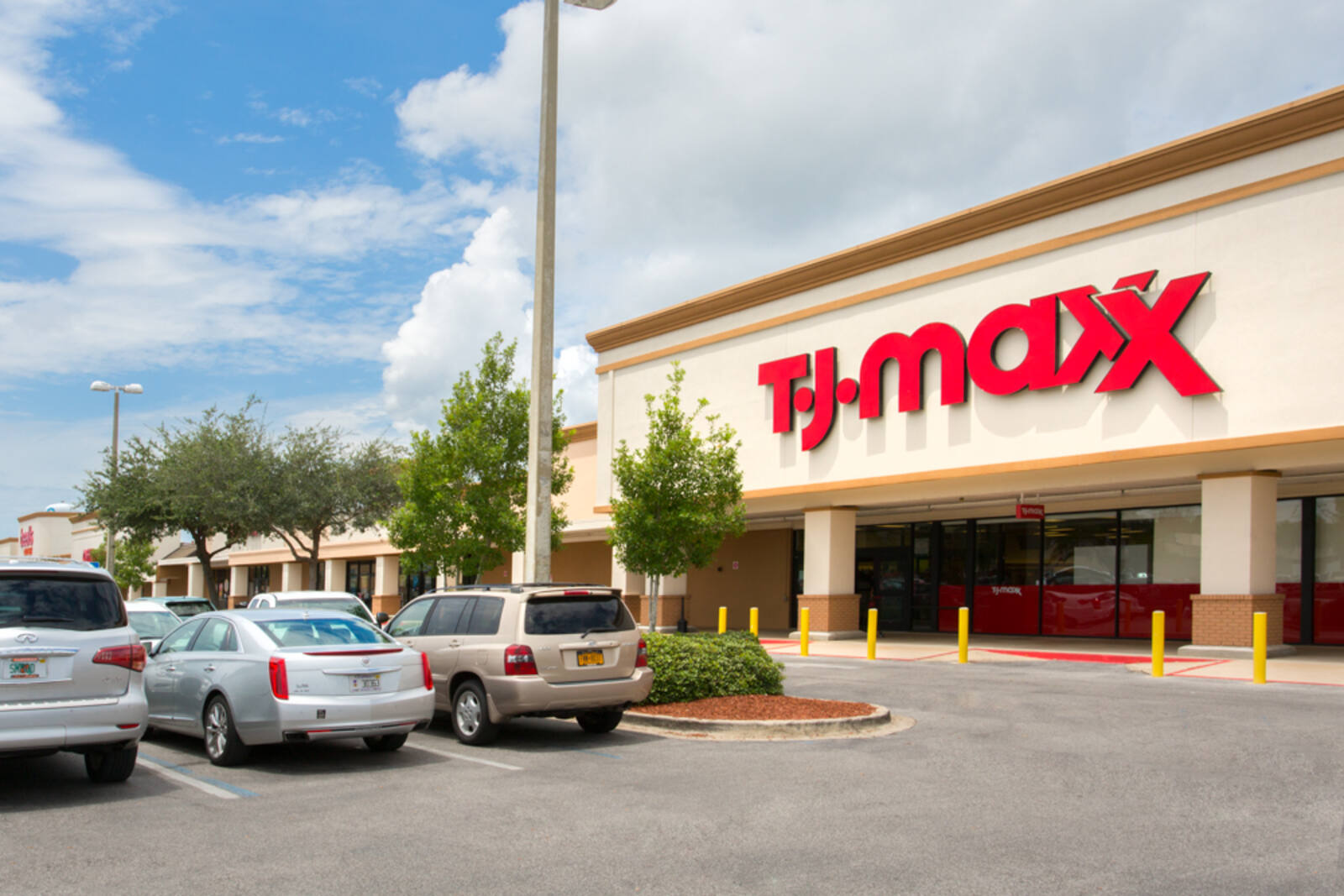 Cars parked in front of tree lined entrance to T.J. Maxx