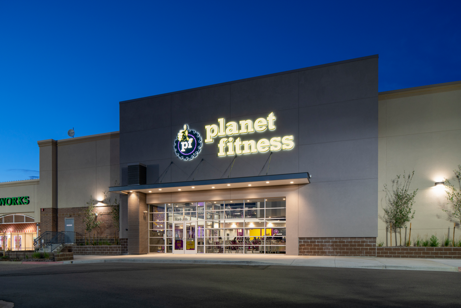 Lit up sign of Planet Fitness at night in Aurora, CO.