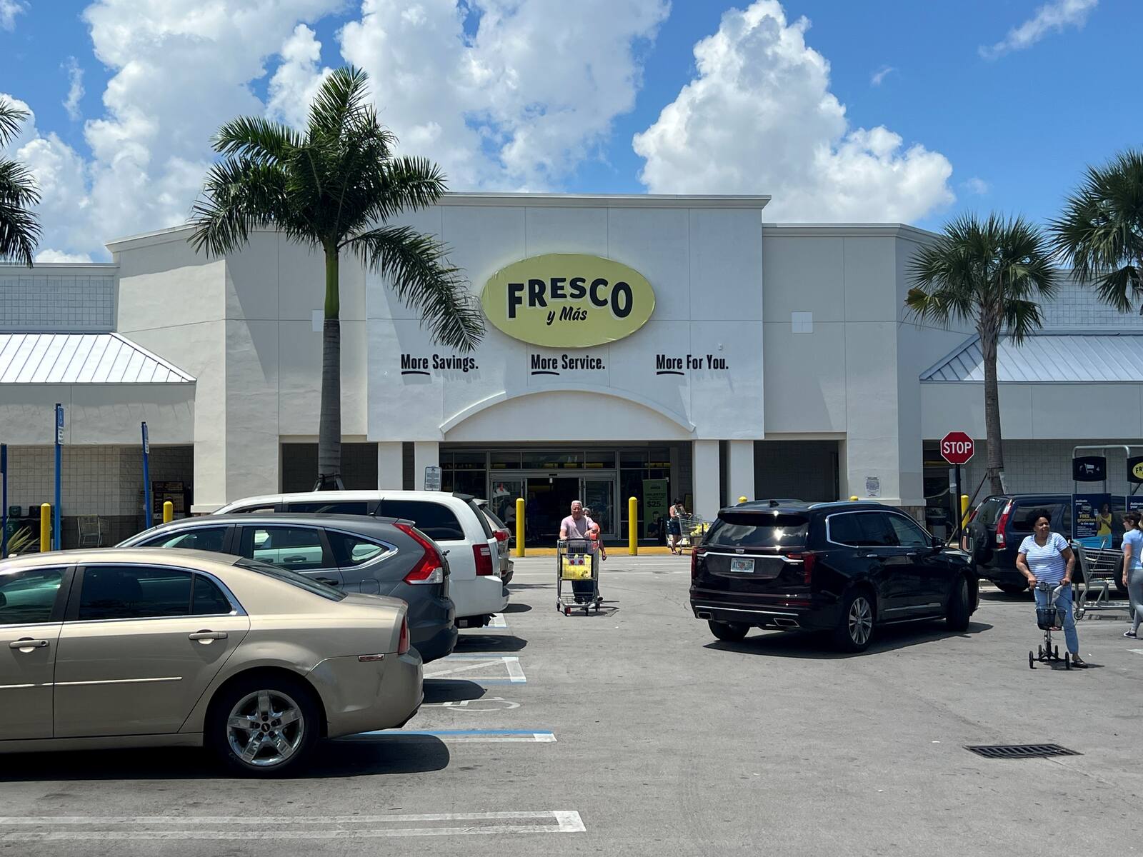 Customers with carts stroll up parking lot at Fresco y Mas Supermarket.