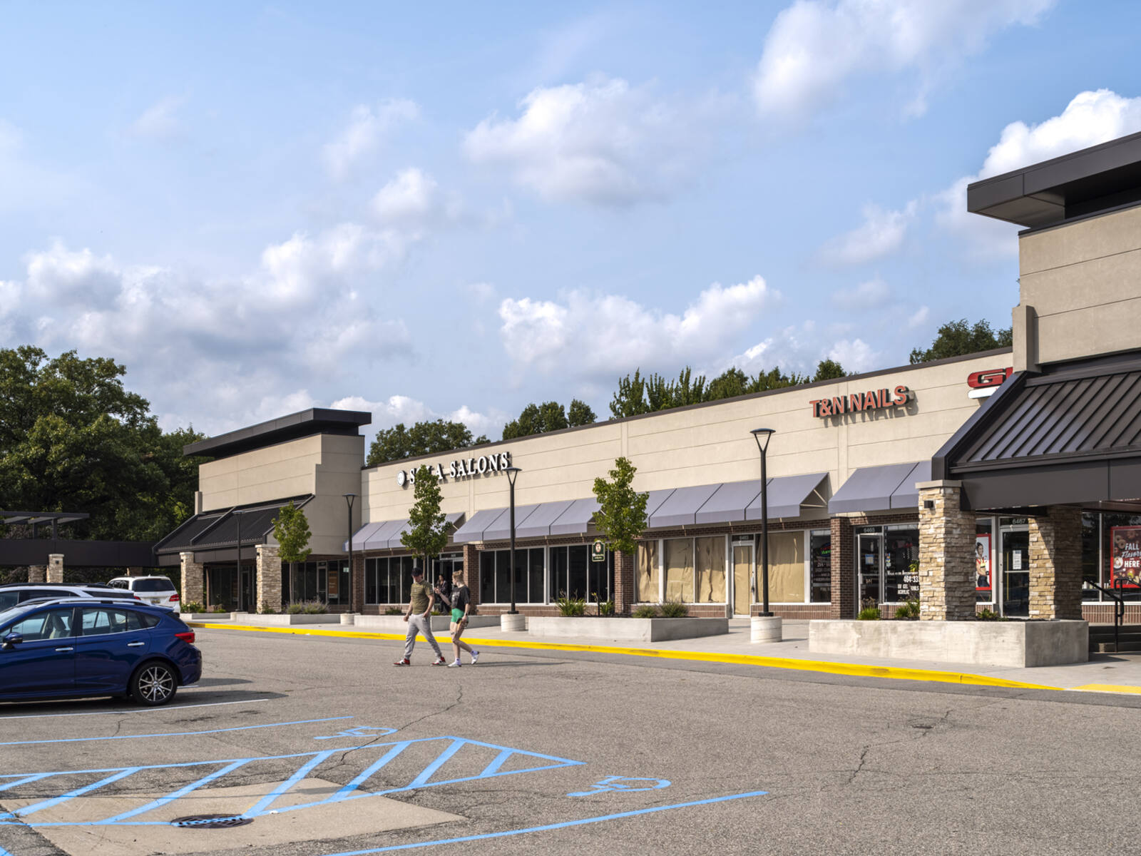 Two pedestrians crossing road at Sola Salons.