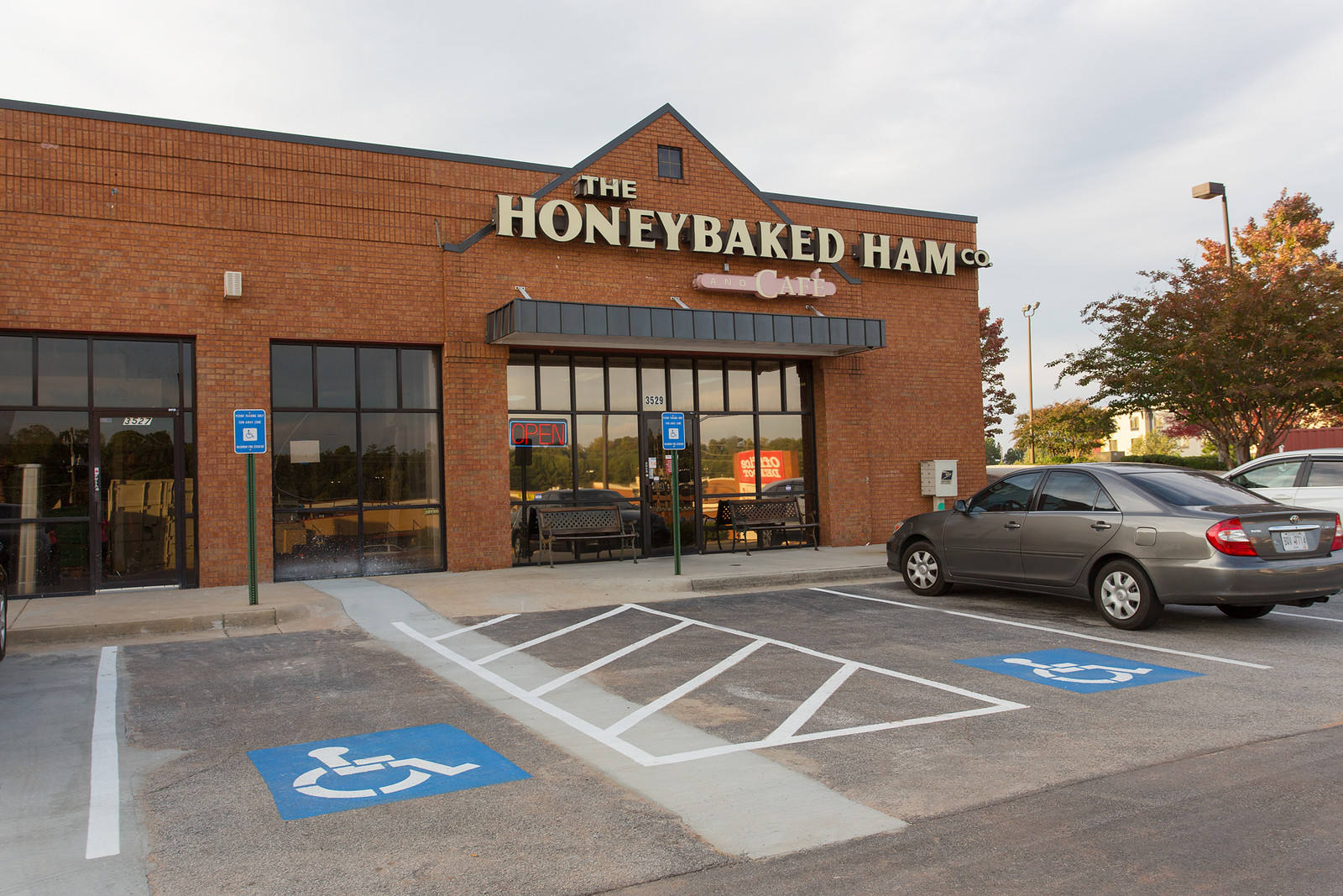 Grey car parked in front of The Honeybaked Ham next to wheelchair accessible parking spots