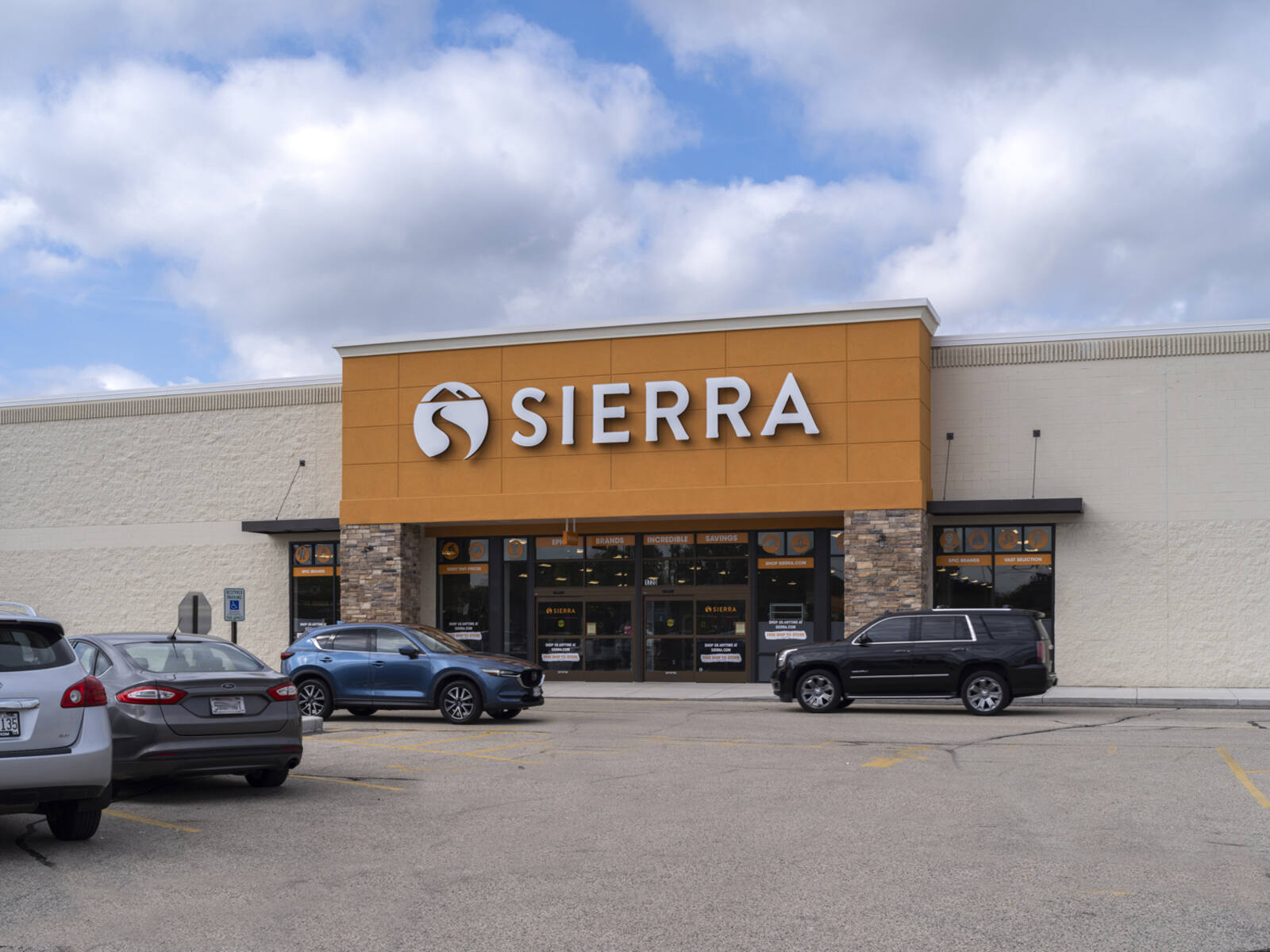 Sierra store facing parking lot with 2 SUVs driving by entrance.