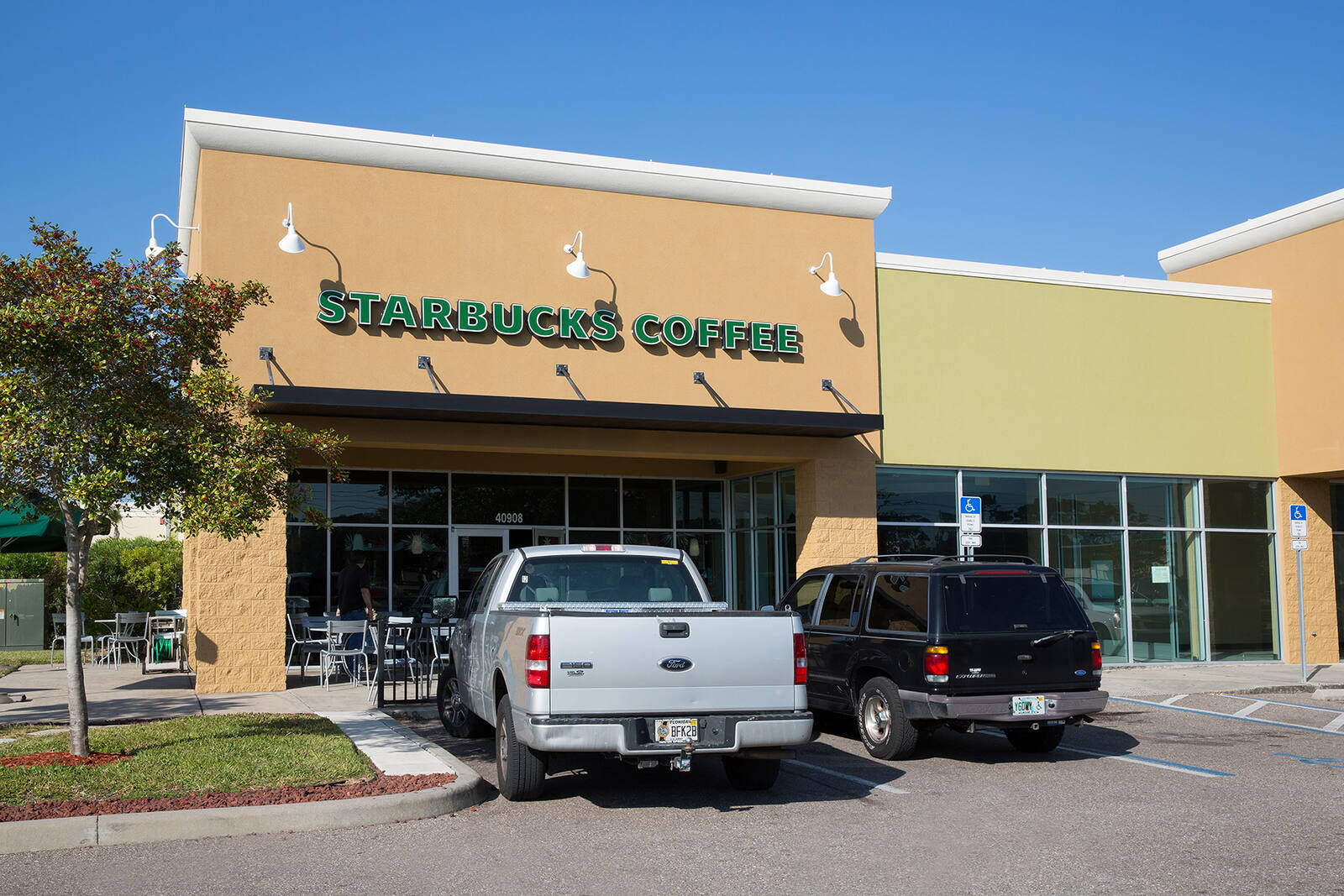 Silver pick up truck and black SUV parked in front of Starbucks Coffee