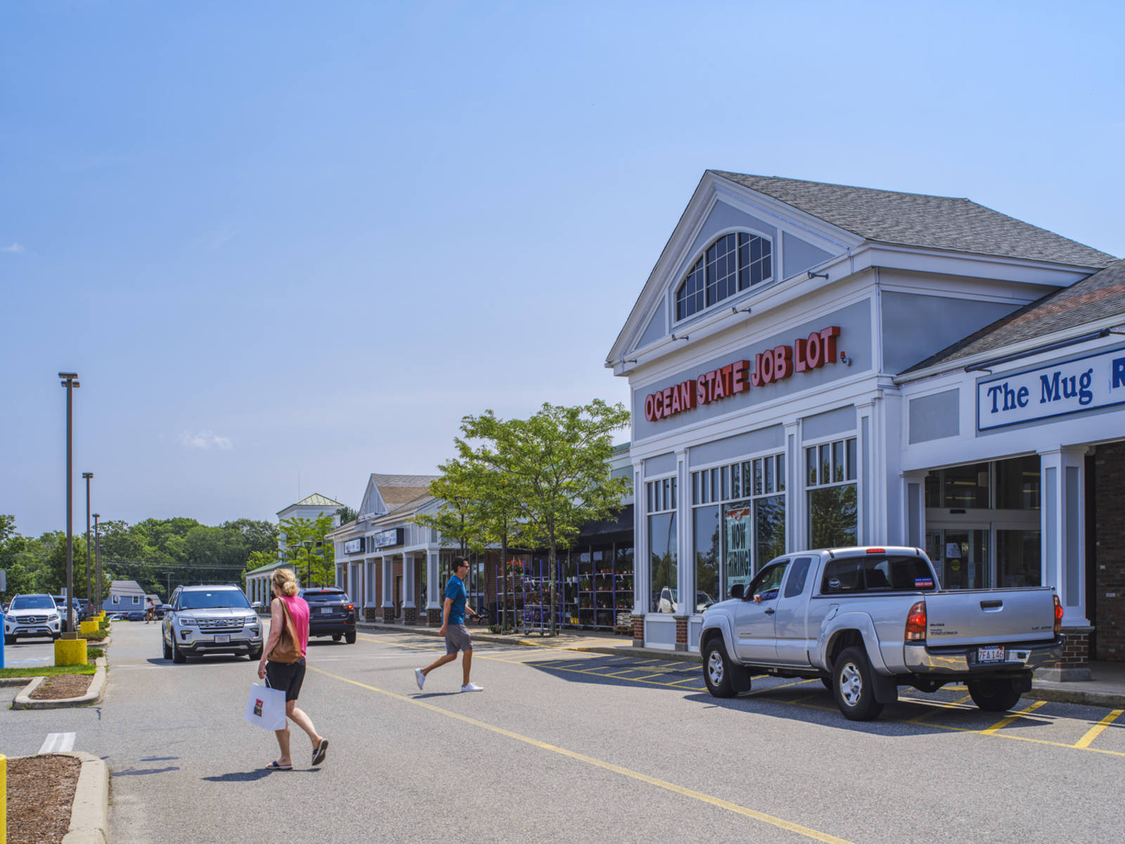 White truck and woman in pink shirt and black shorts in front of Ocean State Job Lot