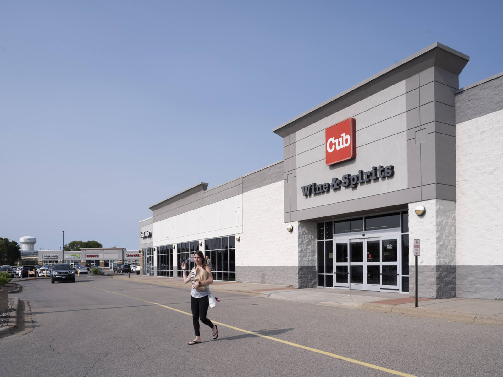 Woman with bag exiting Cub Wine & Spirits into the parking lot.