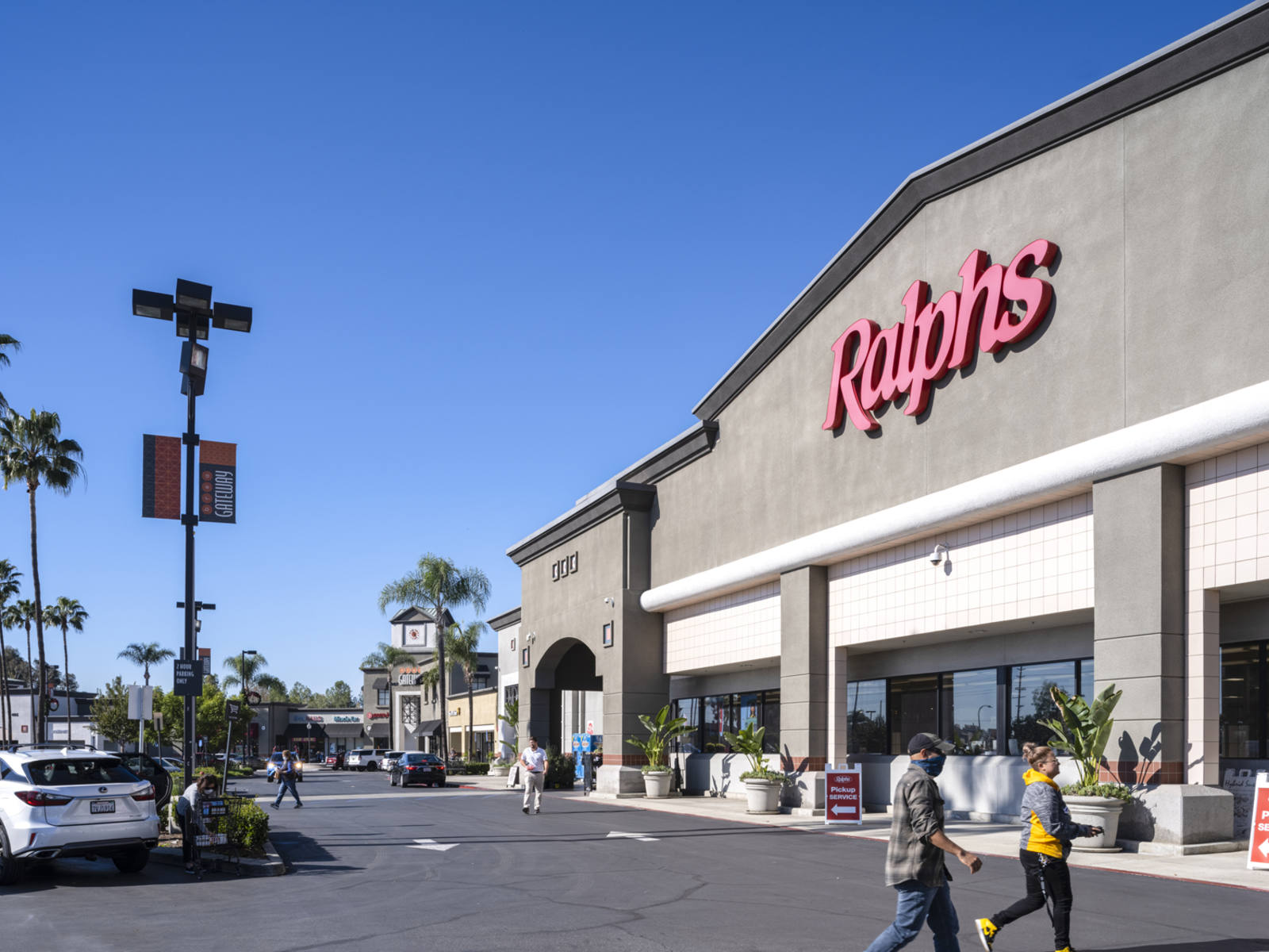 Palm trees and pedestrians in the parking lot for Ralphs grocery store in Brea, CA.