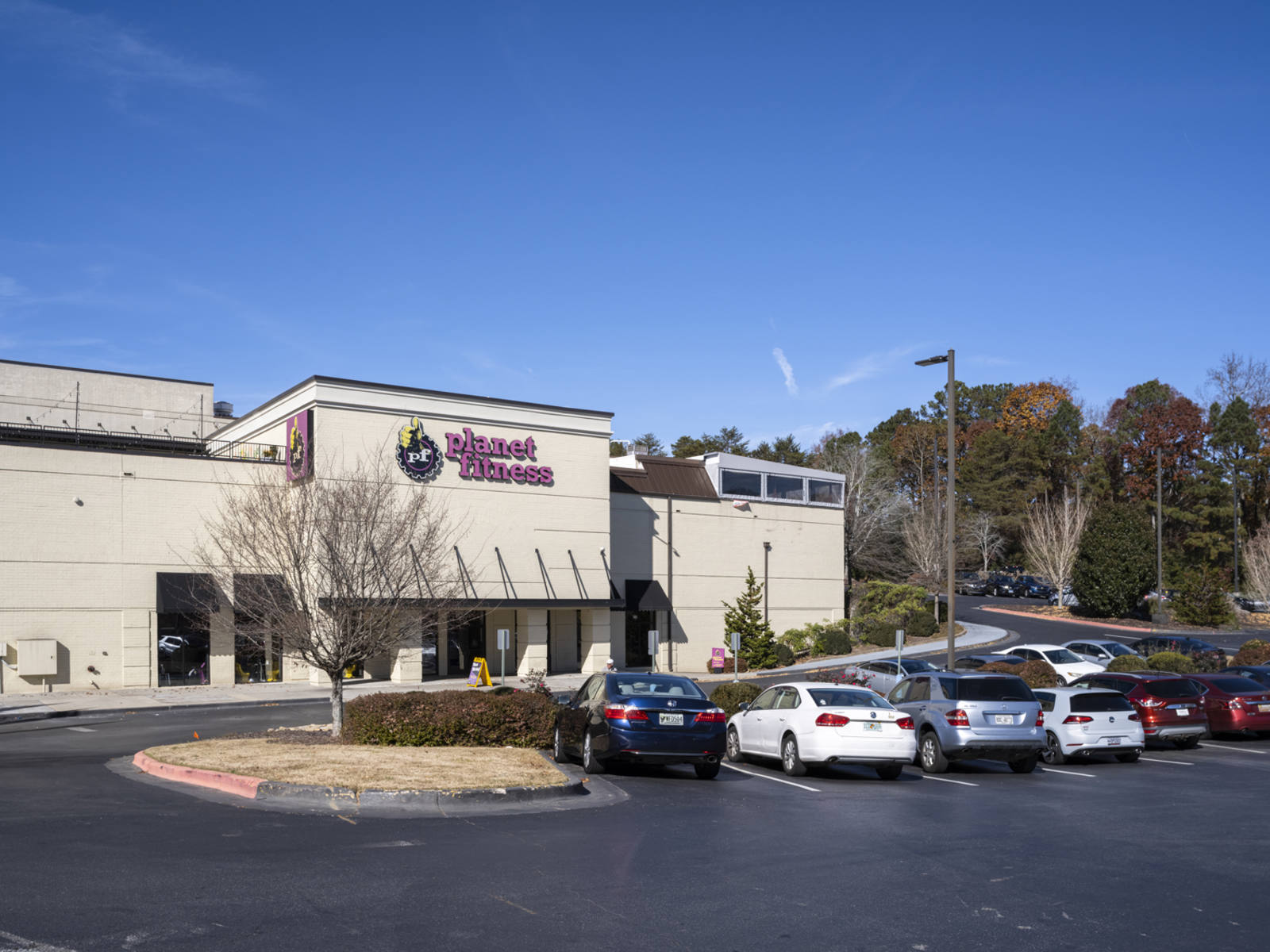 Planet Fitness with trees and full parking lot at Connexion shopping center.