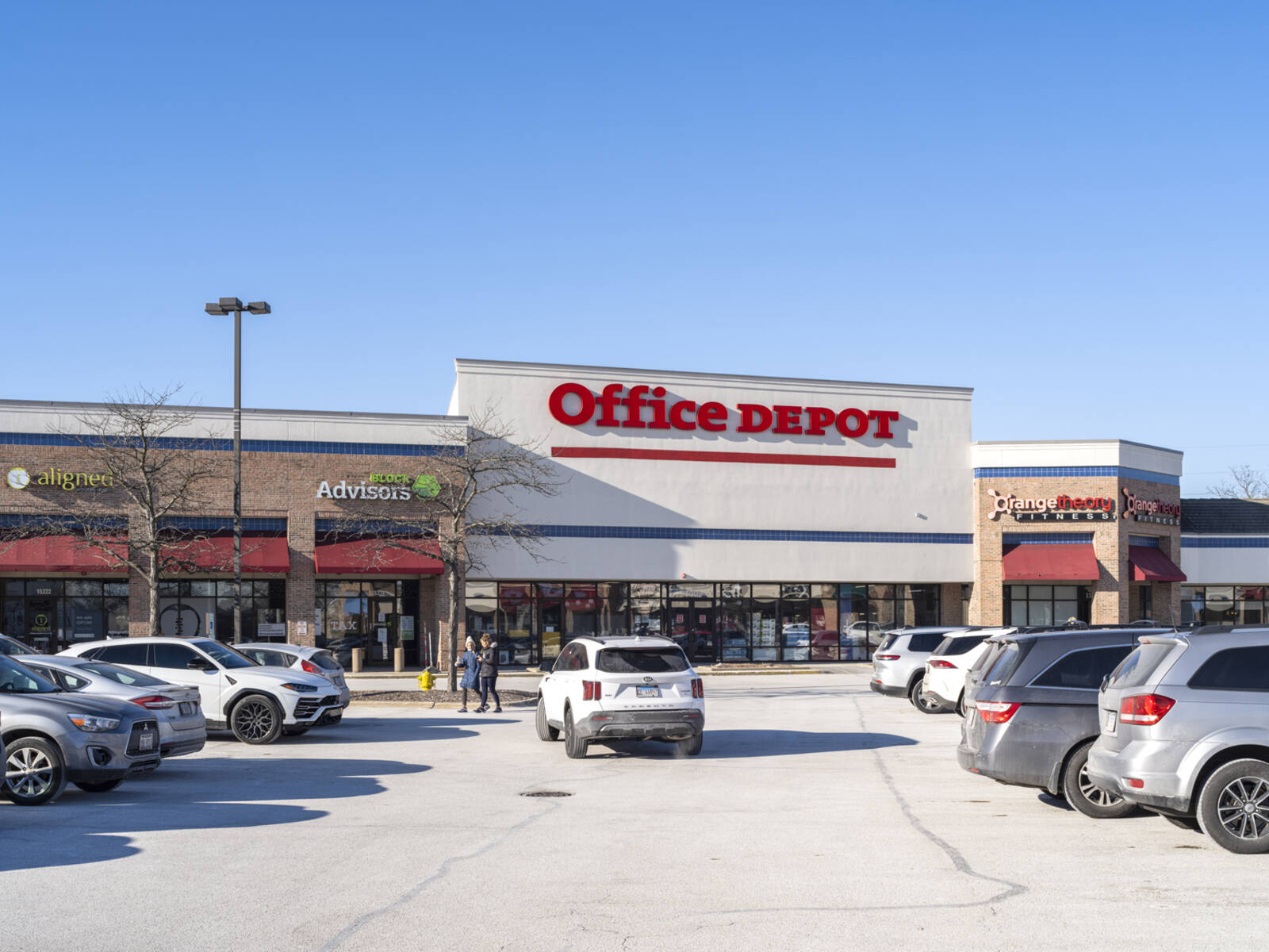 White SUV driving through parking lot of Office Depot at outdoor shopping center in Orland Park, Illinois