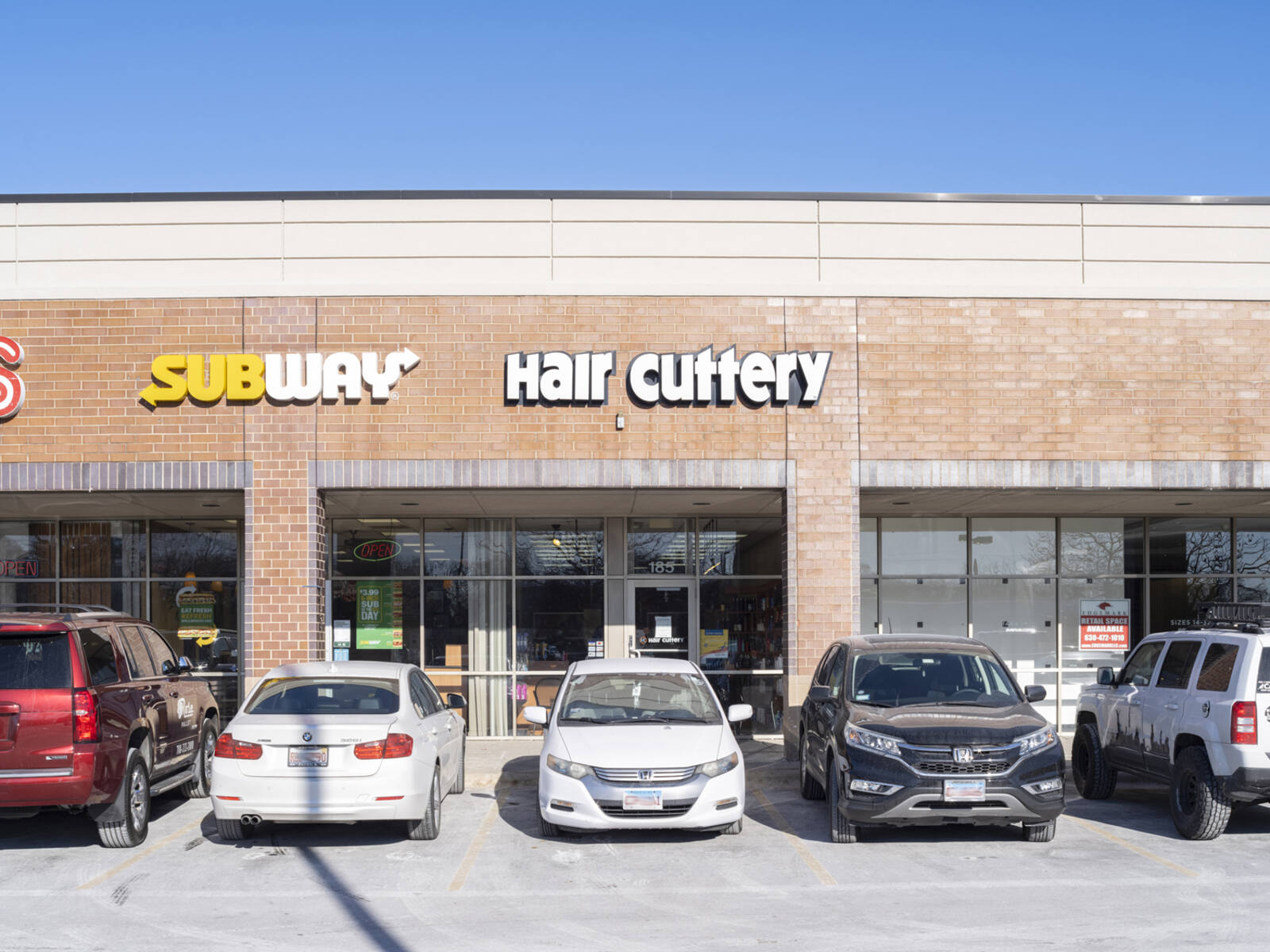 Subway and Hair Cuttery with cars parked in front at Elmhurst Crossing.