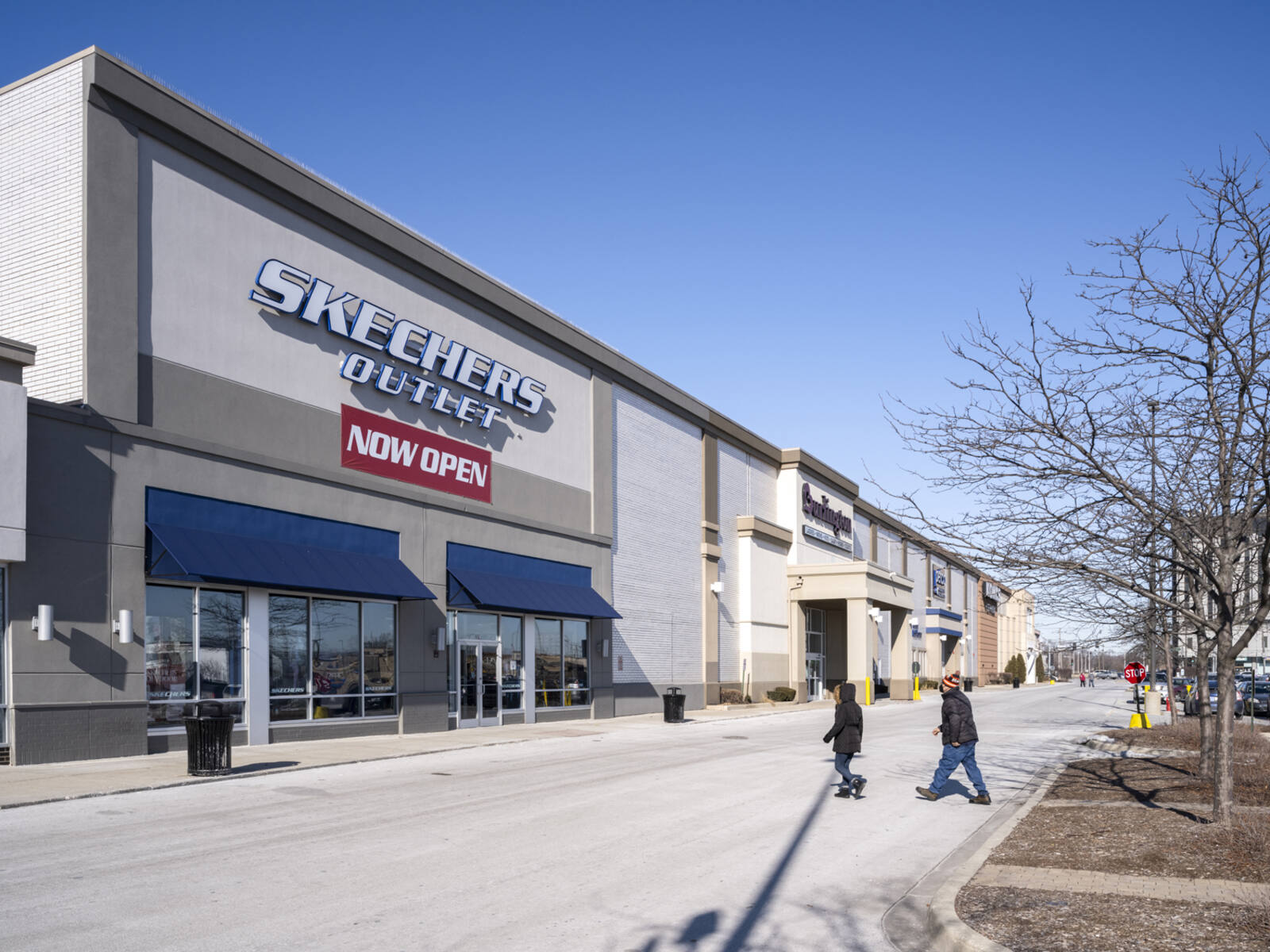 Shoppers cross road to enter Skechers Outlet at North Riverside Plaza.