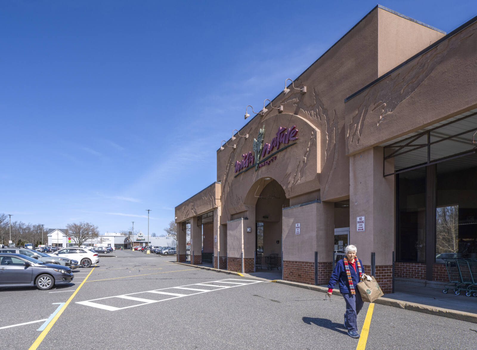 Woman exits Wild By Nature grocery store to access road at West Center.
