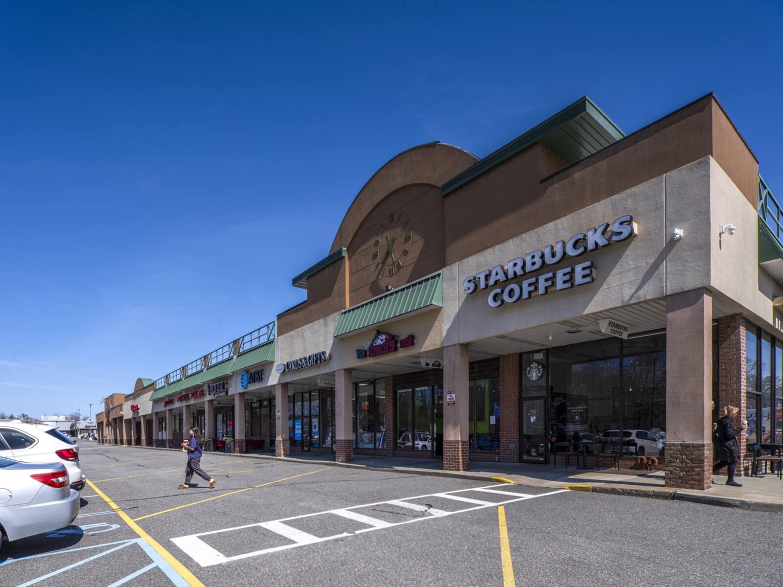 Woman exits Starbucks Coffee into parking lot.