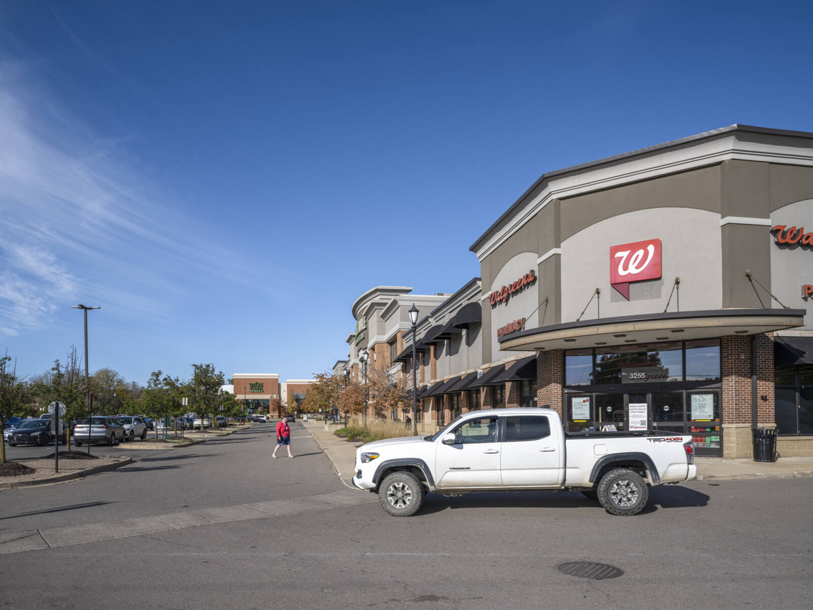 White truck on road in front of Walgreens and parking lot.