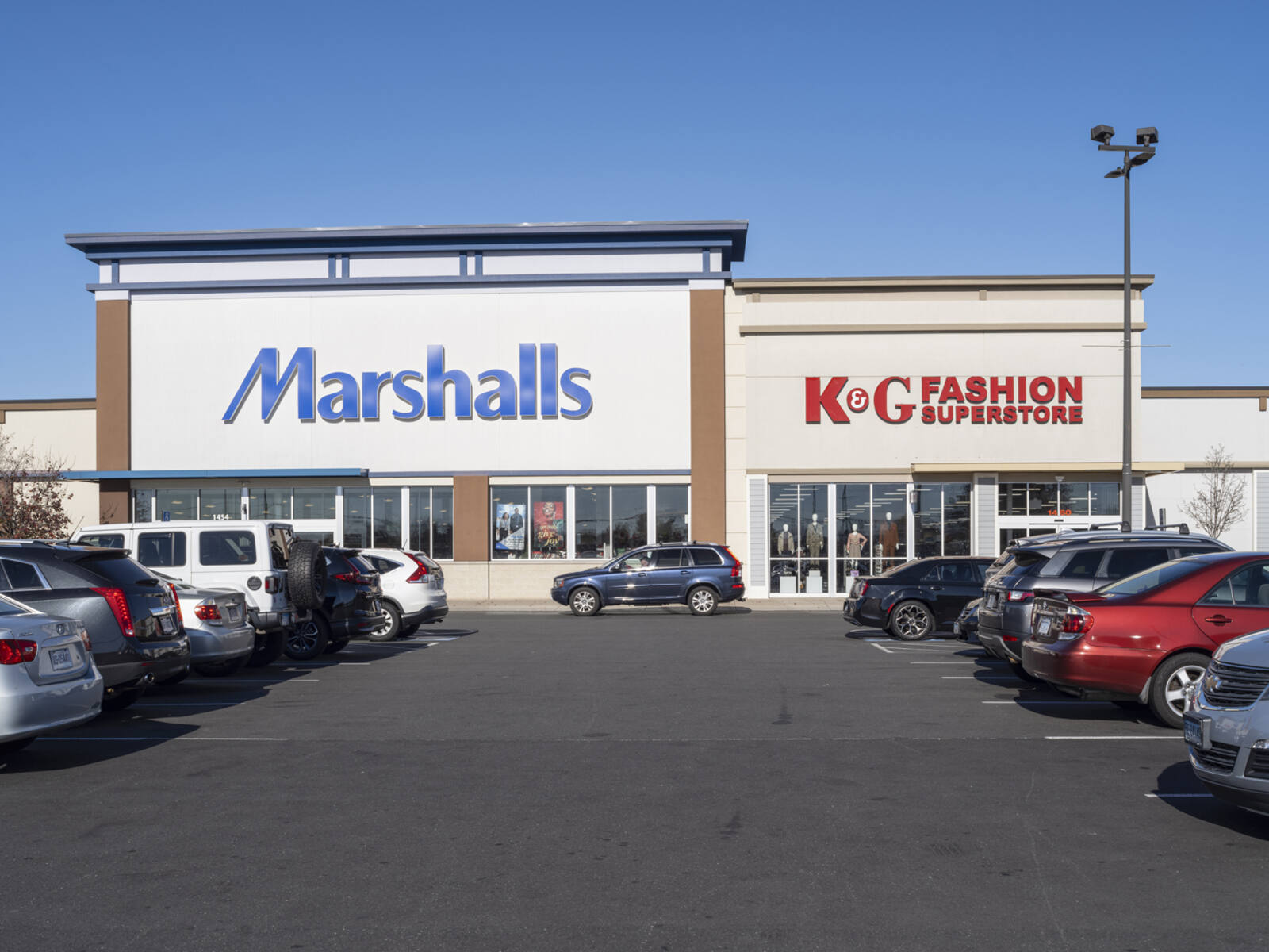 2 rows of parked cars in lot for Marshalls and K & G Fashion.