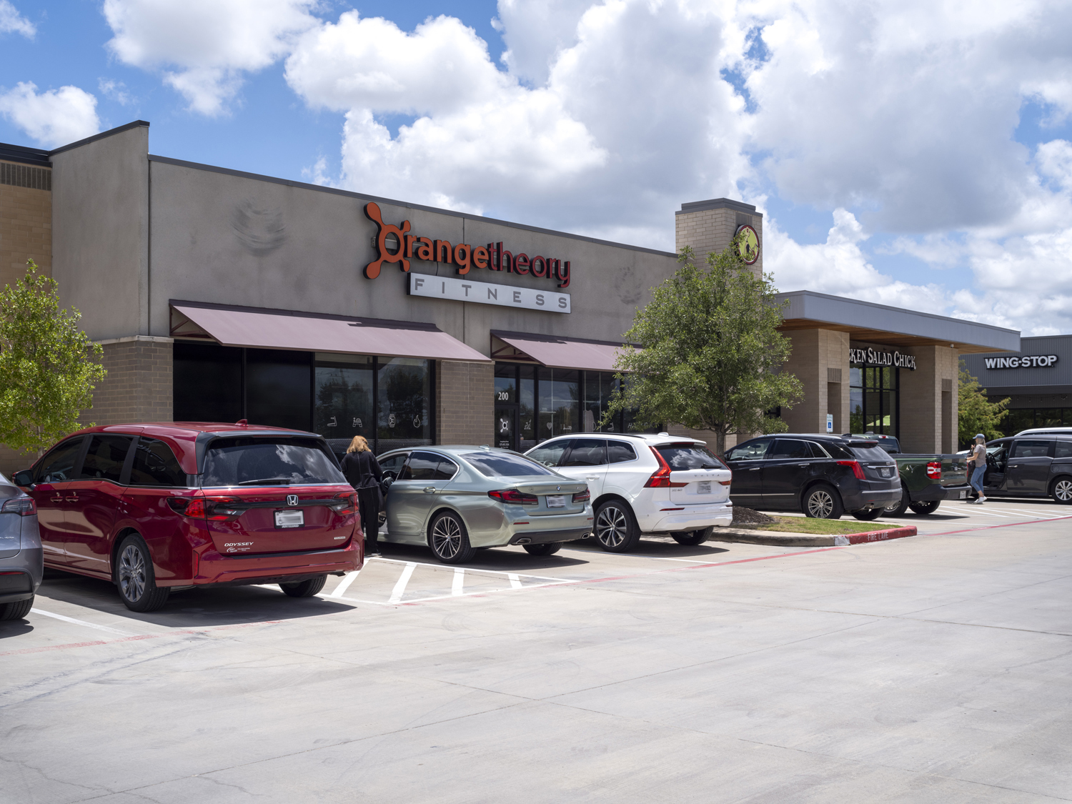 Customers exiting their cars at parking lot at Orangetheory Fitness