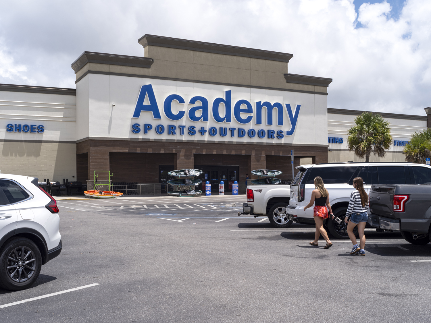 Customers approach Academy Sports through the parking lot.