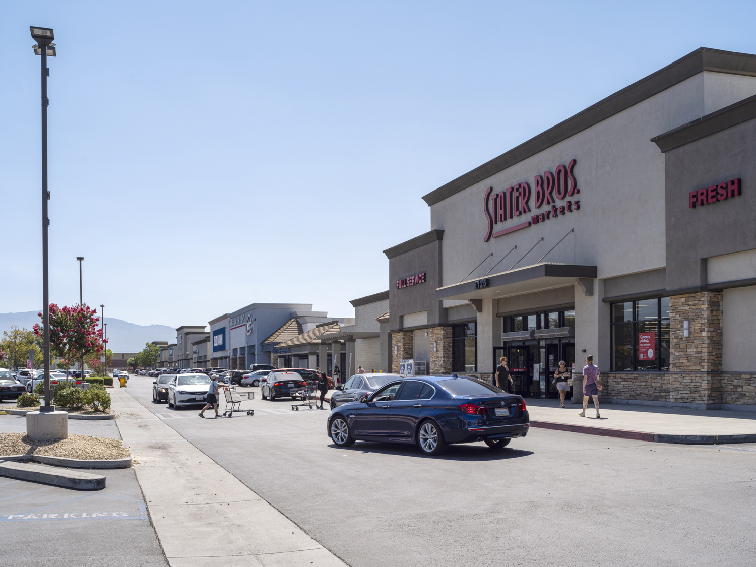 Shoppers and cars on busy road in front of Stater Bros. Market