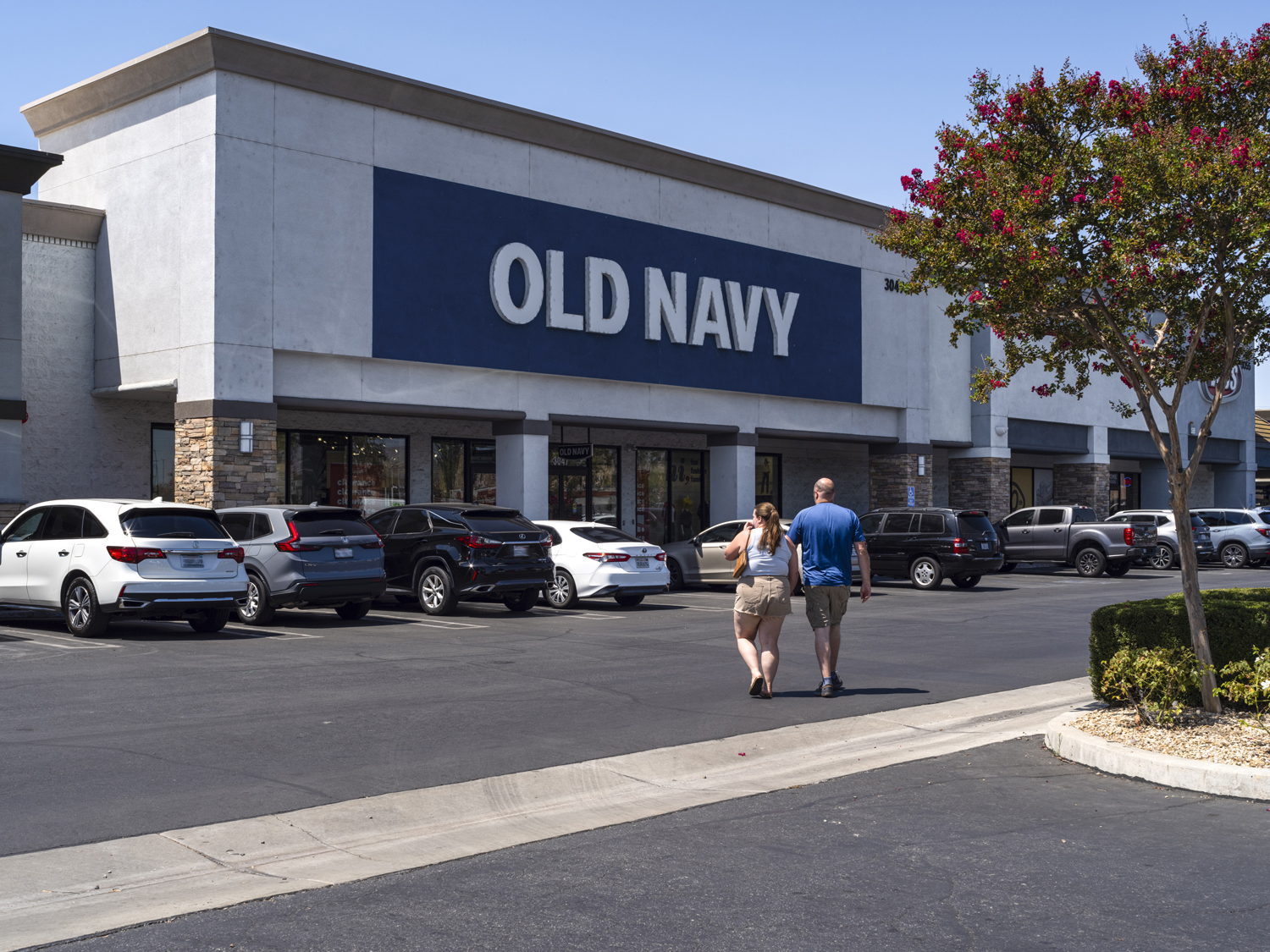 Two people crossing the road to parking lot and Old Navy.