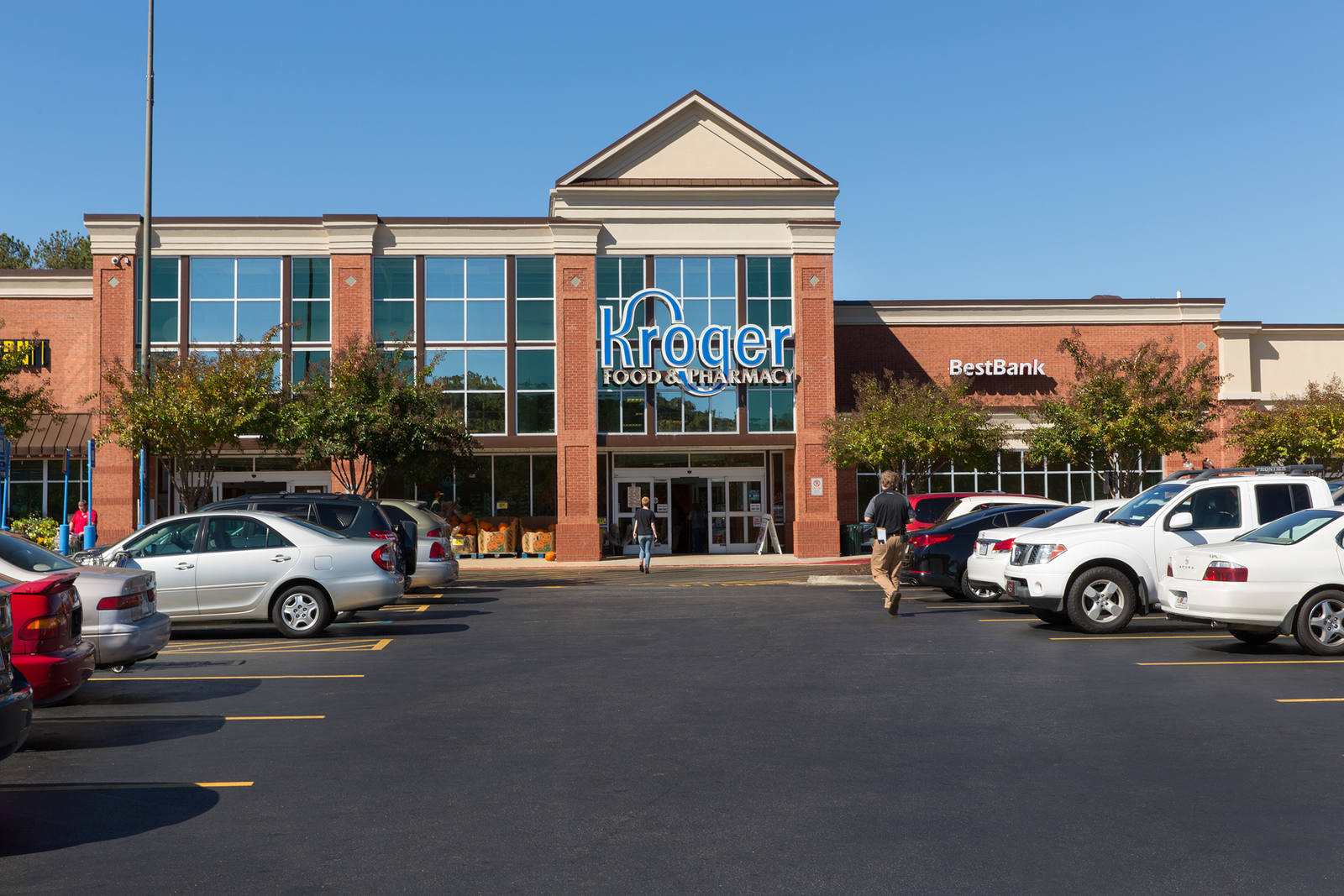 Customers enter Kroger supermarket in a tree-lined parking lot in Cumming, GA.