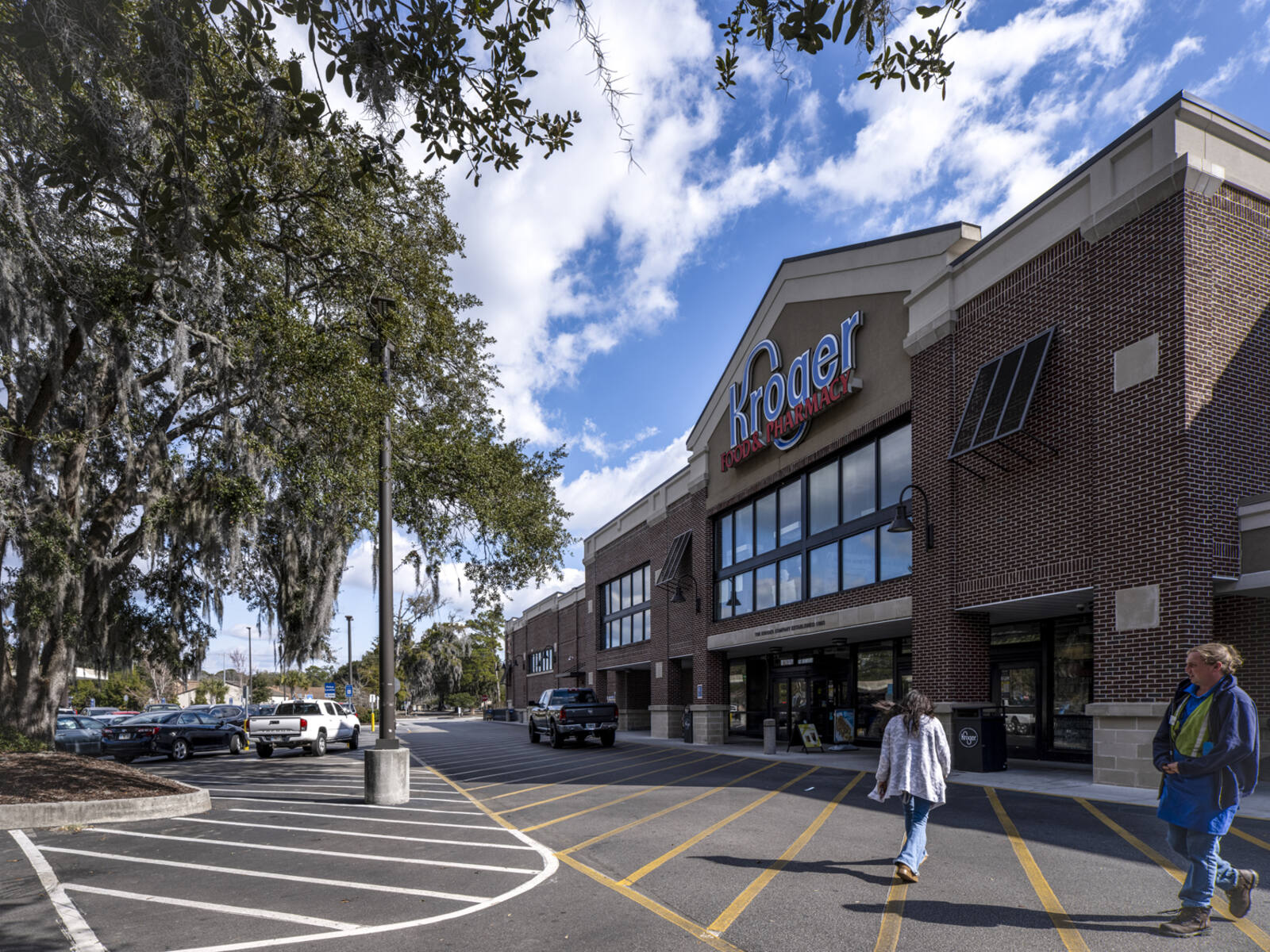 Patrons at entrance of Kroger supermarket with trees and parking lot in front.