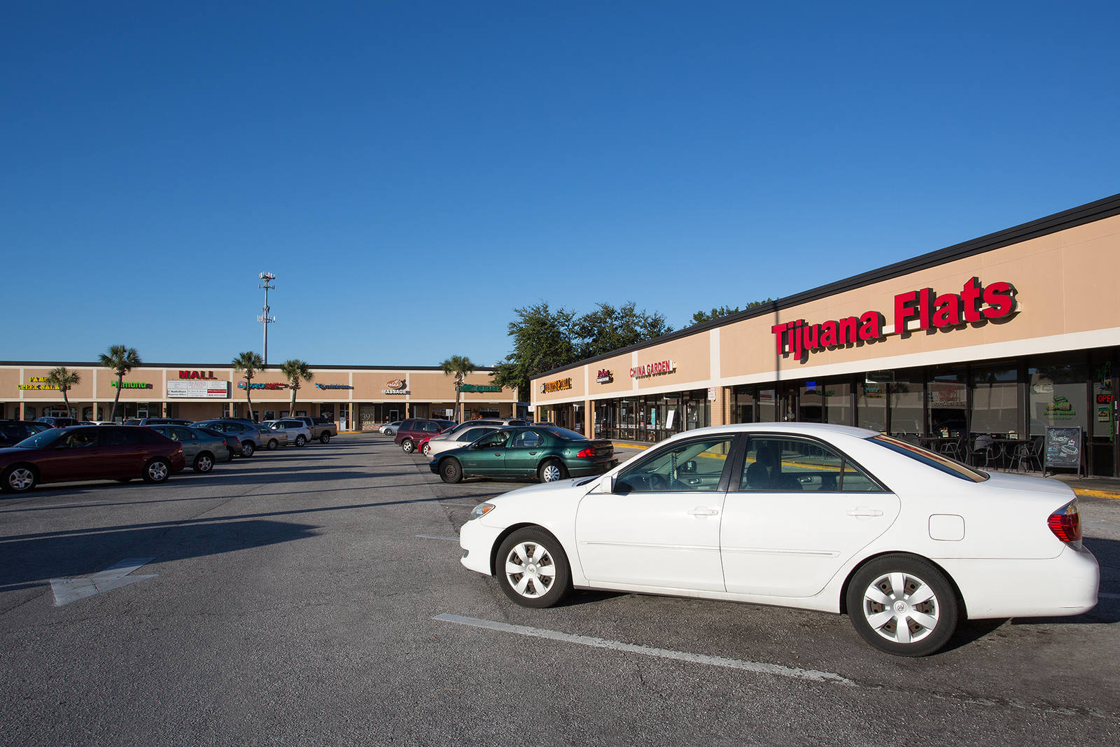 White car in the parking lot of Carrollwood Center amongst inline retailers.
