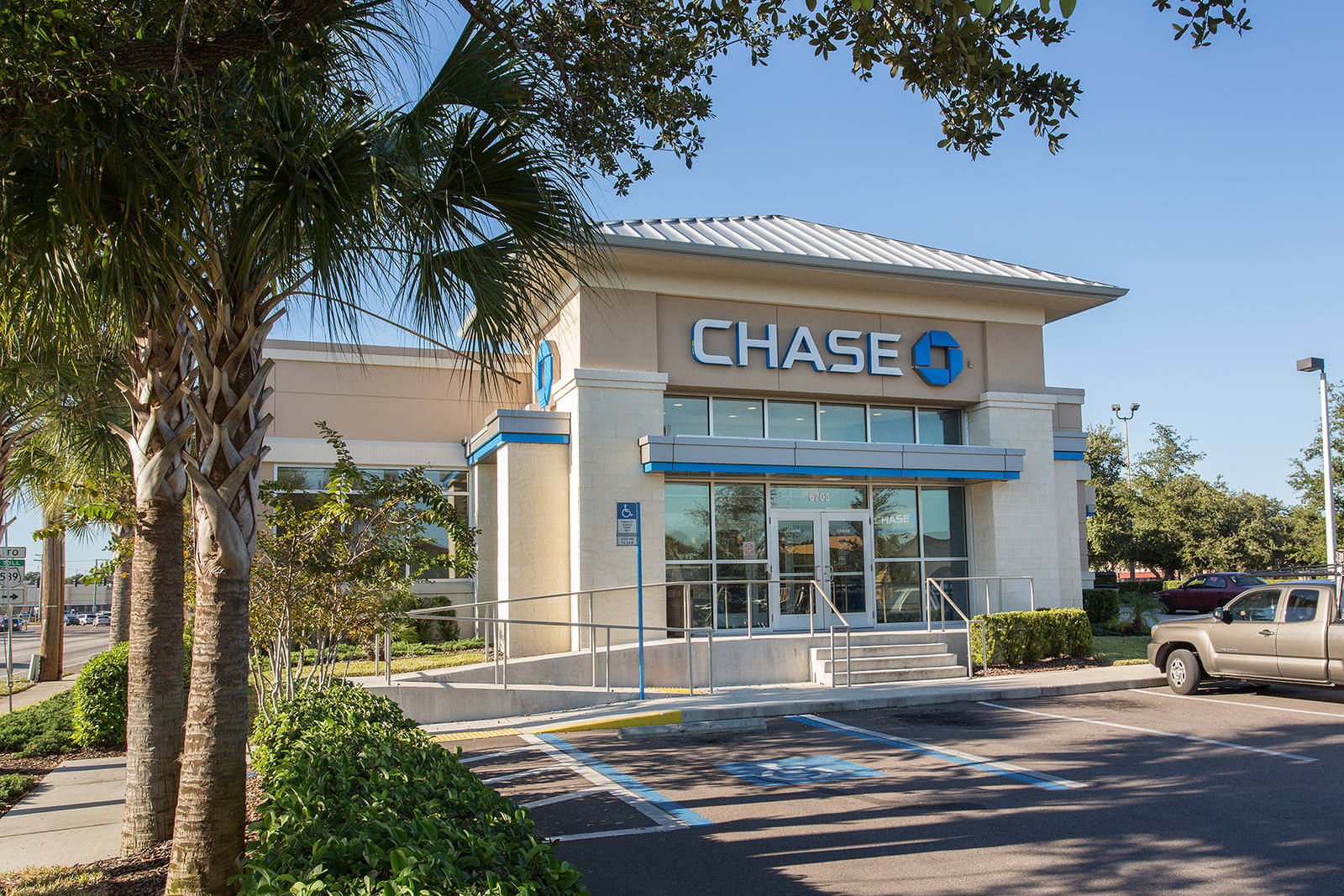 Palm trees lining left entrance of Chase Bank with parked tan pick up truck in front
