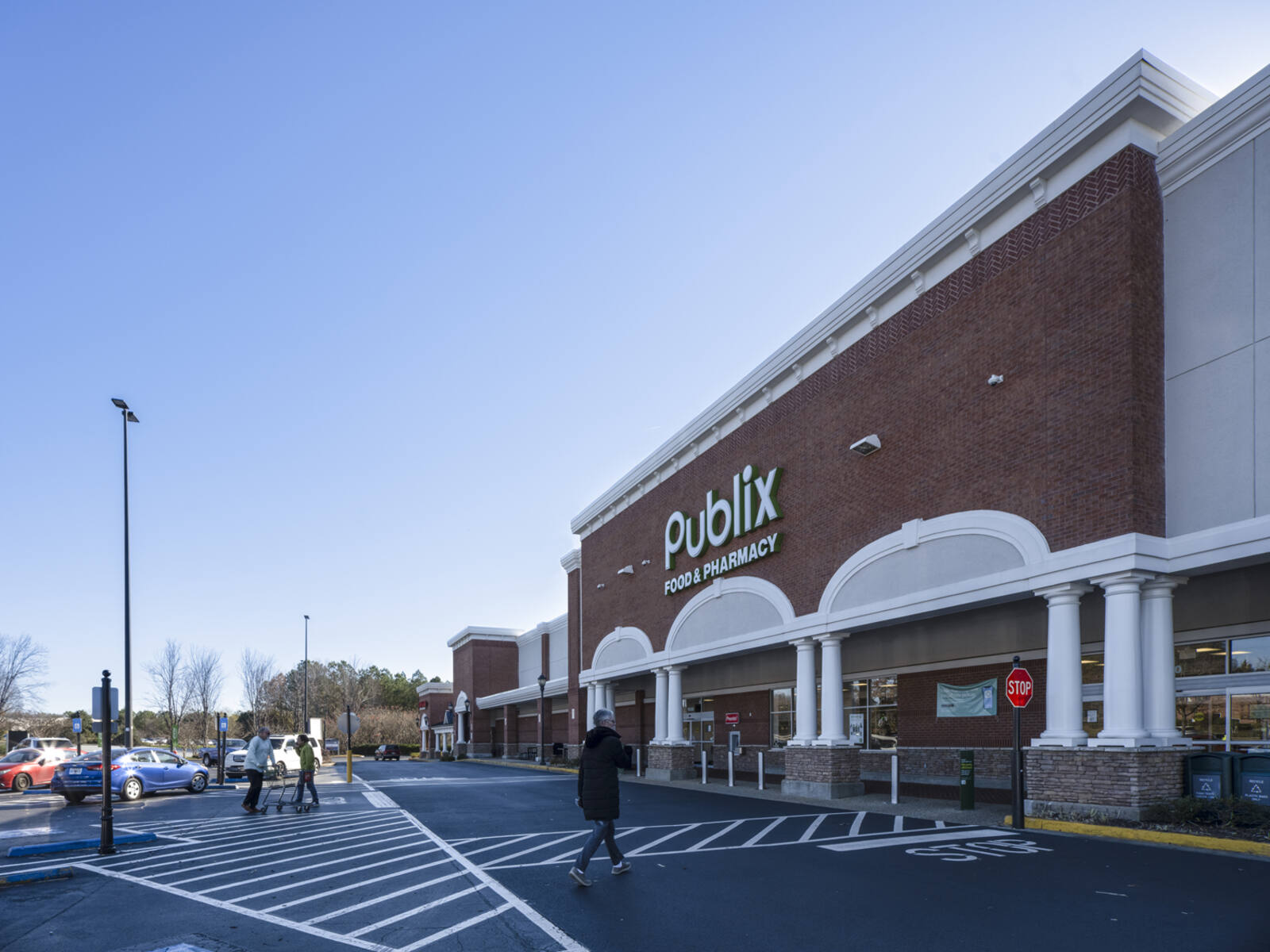 Pedestrians approach Publix via crosswalk in shopping center.