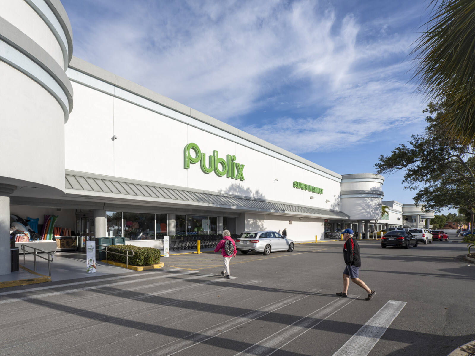 Pedestrians crossing walkway towards Publix grocer.