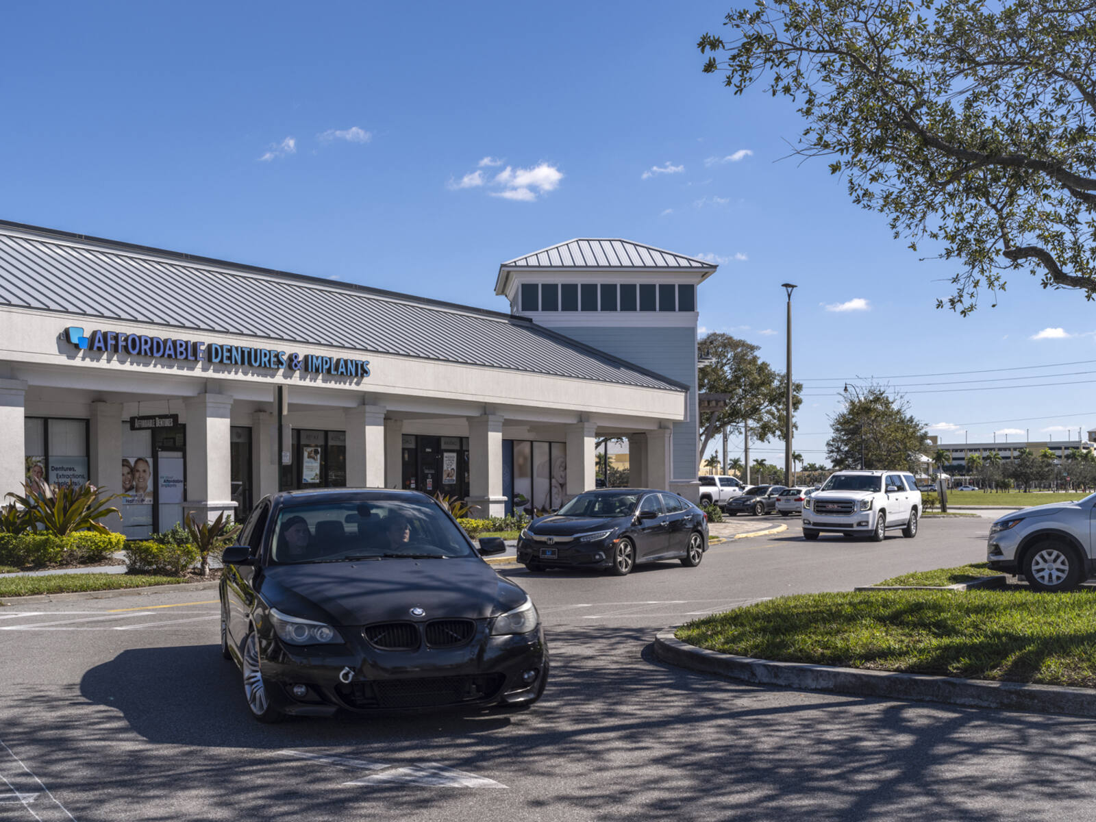 Cars in line making a turn in front of Affordable Dentures & Implants.