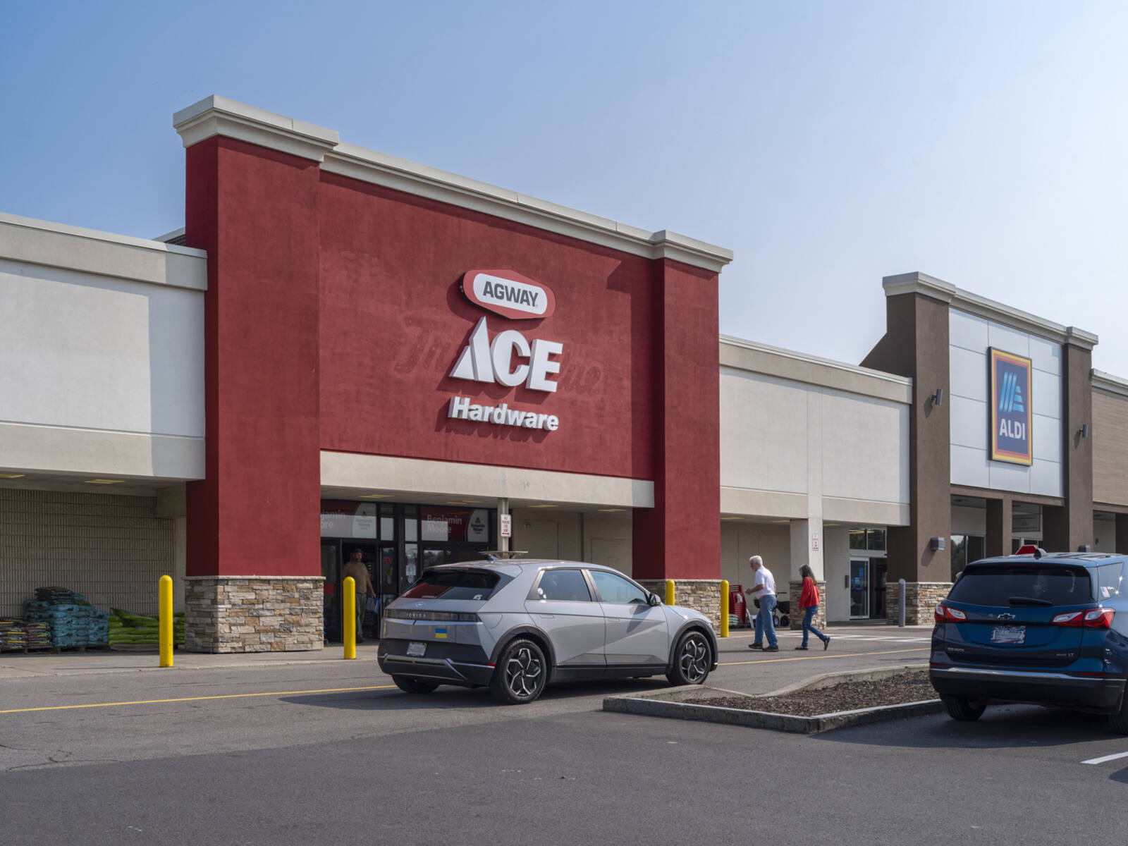 Grey SUV and customers on road in front of Ace Hardware.