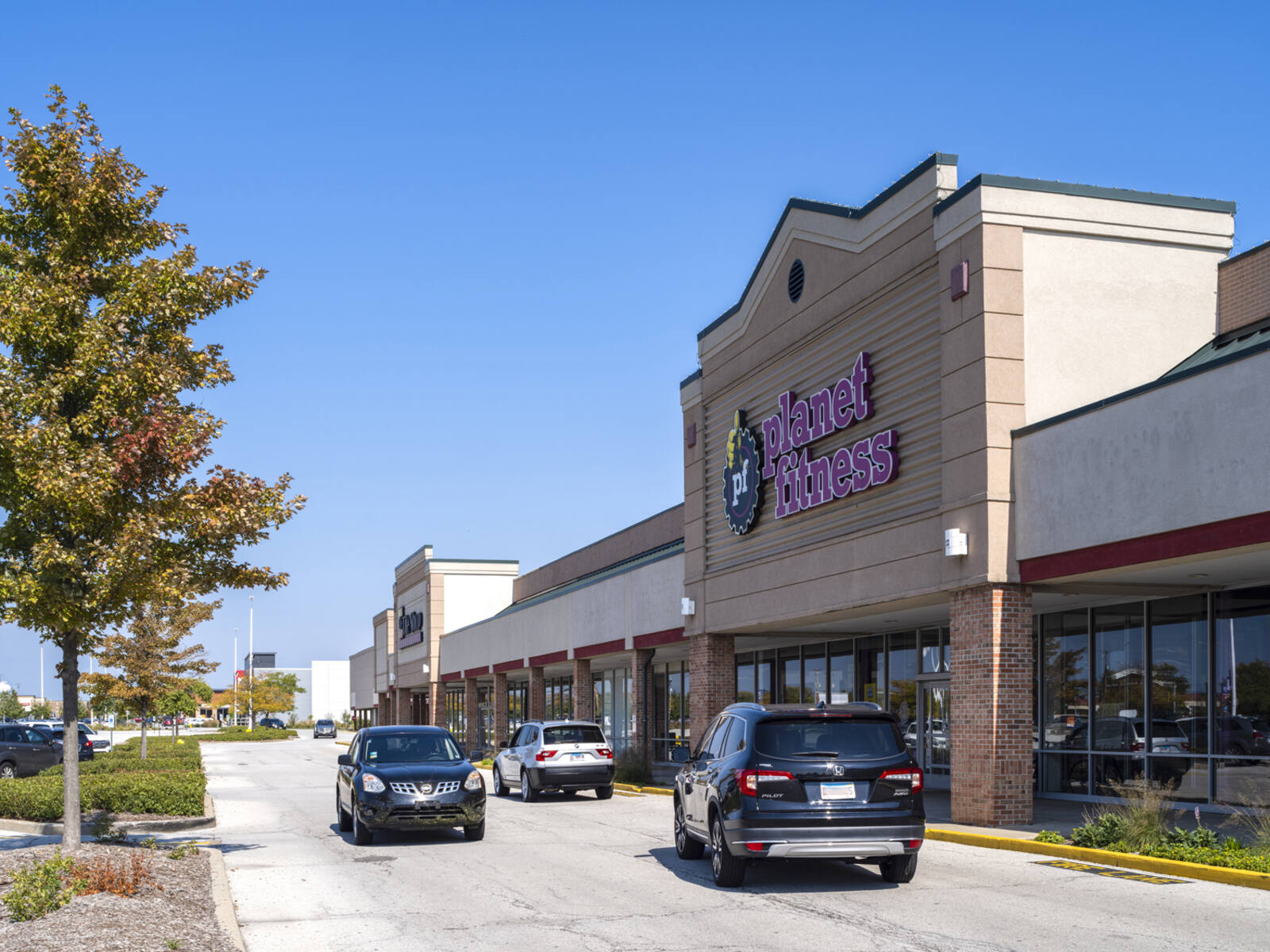 Planet Fitness gym with cars passing front entrance.