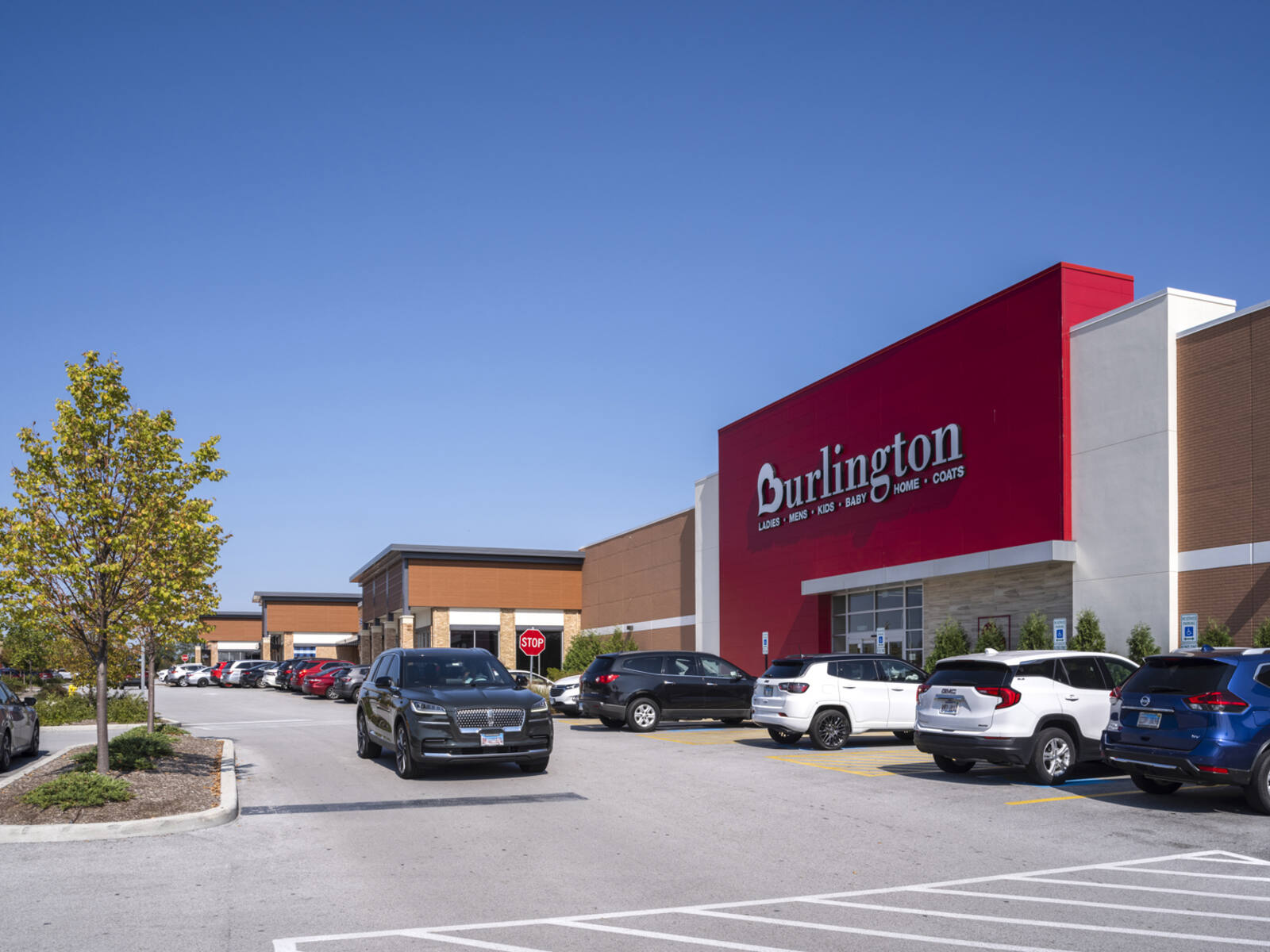 Burlington store with buys parking lot in front and tree planter on corner of intersection.