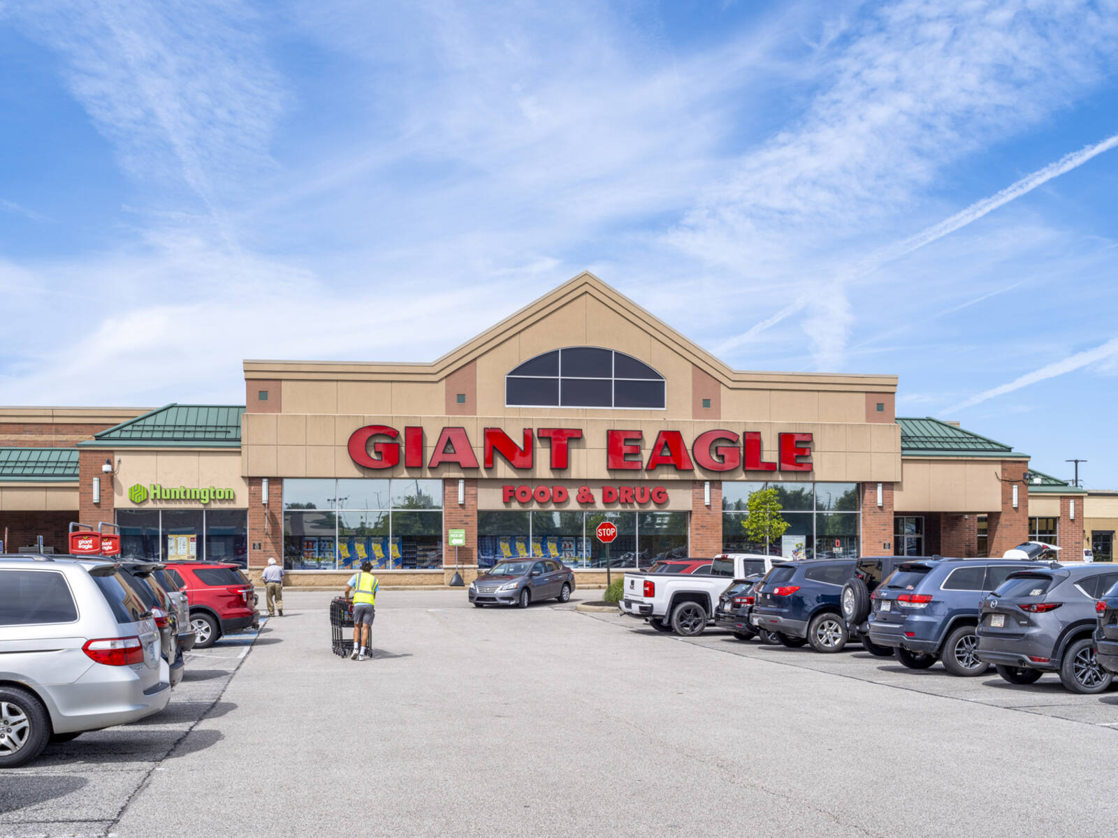 Shoppers walk down aisle of cars in parking lot of Giant Eagle supermarket at Brunswick Town Center.