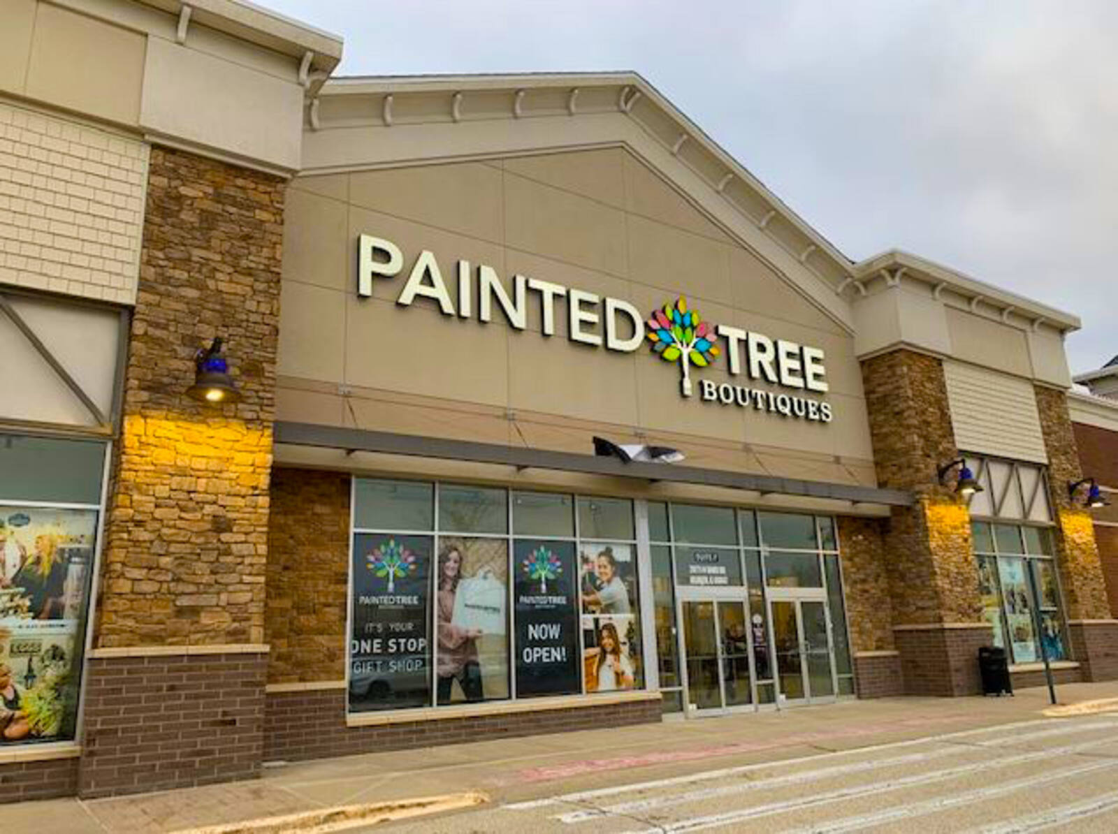 Storefront of Painted Tree Boutique with yellow lights and posters by the doorway.