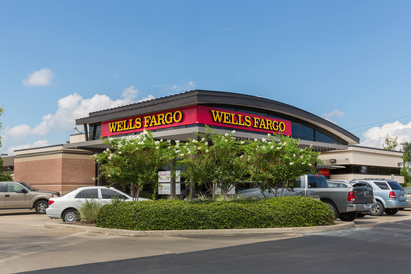 Shrubs and small trees in front of the parking lot at Wells Fargo bank.