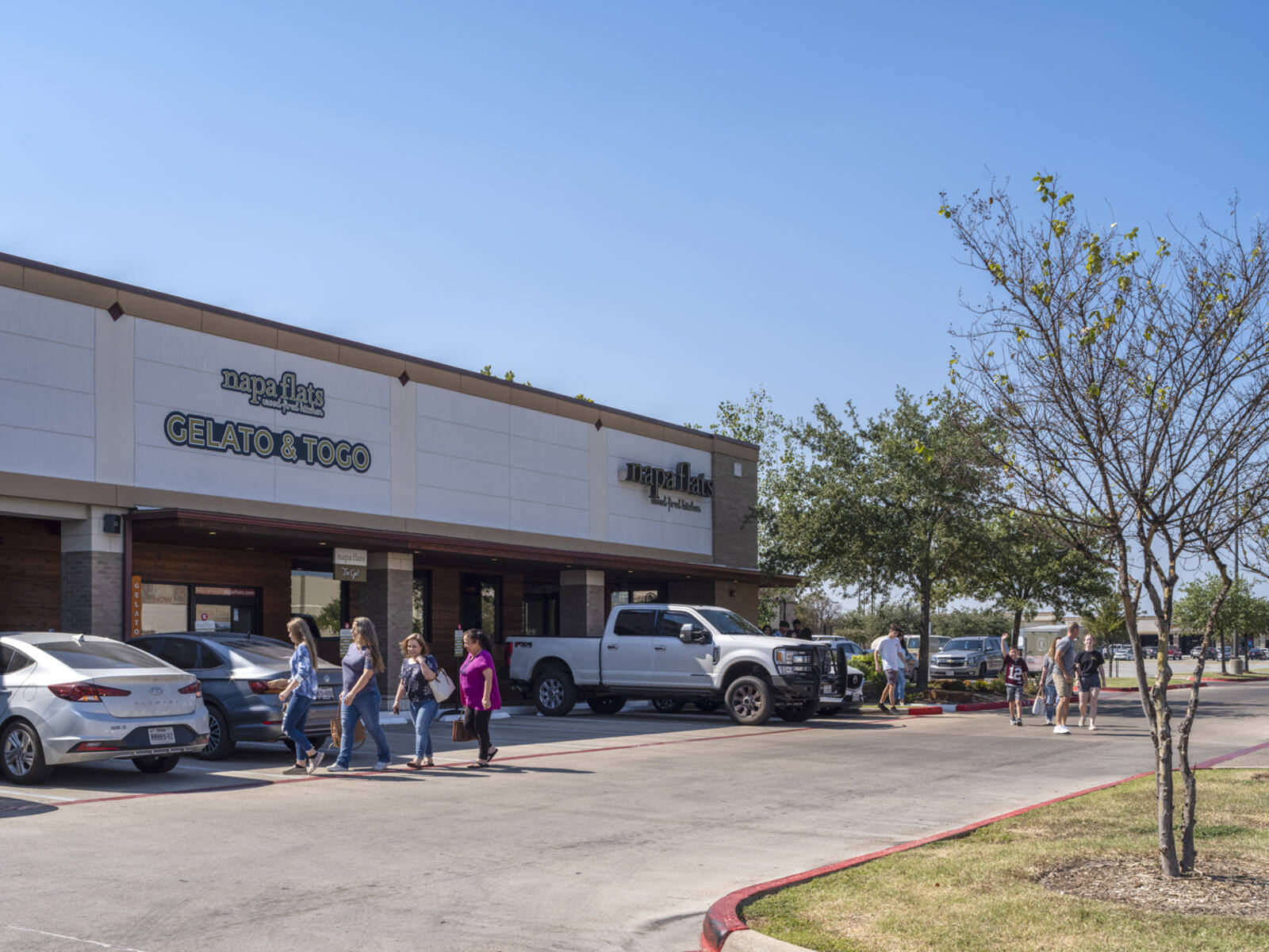 Group of women walking in parking lot of Napa Flats while a family follows behind them.