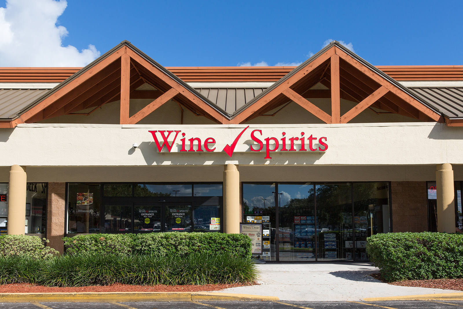 Green hedges line entrance of Winn Dixie Wine and Spirits